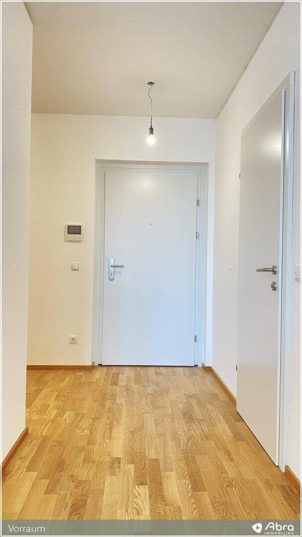 Heller Eingangsbereich mit Holzboden und weißer Eingangstür, modern und einladend gestaltet.