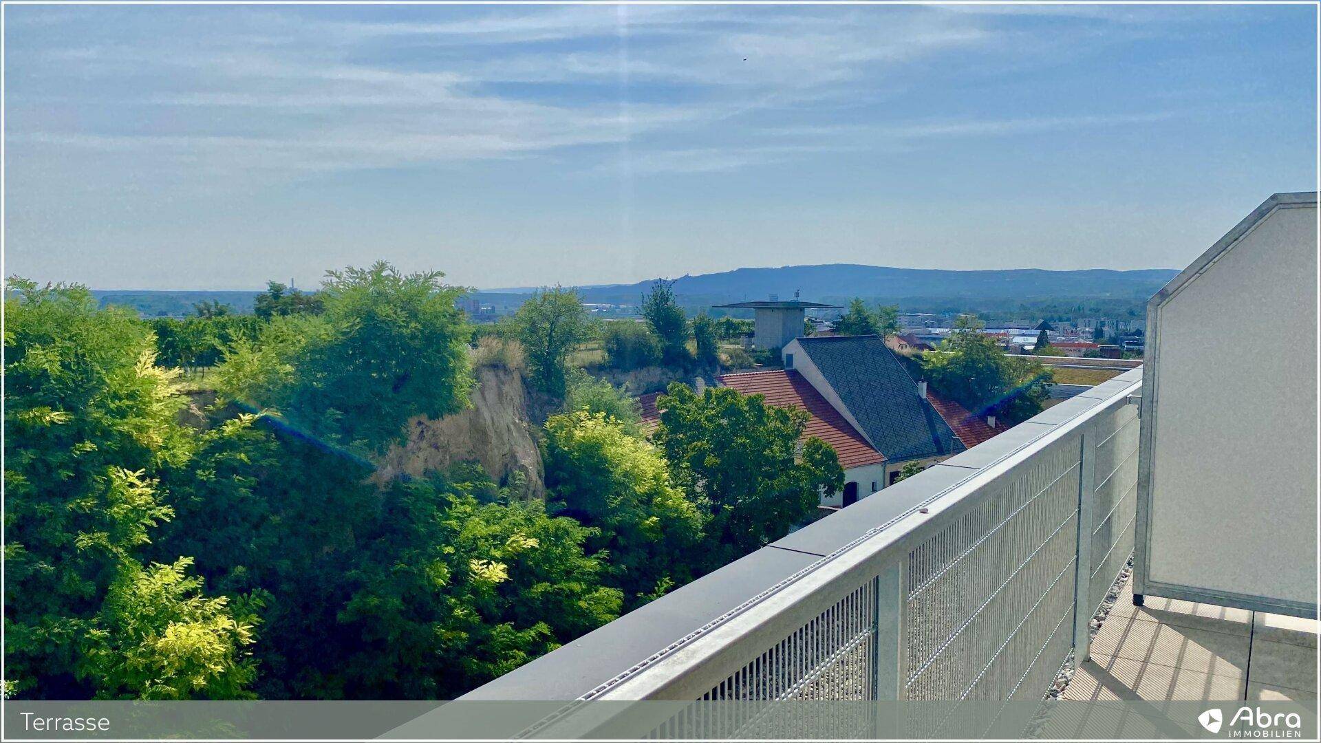 Terrasse mit Blick auf die umliegende Wohnbebauung und die grünen Hügel in der Ferne.