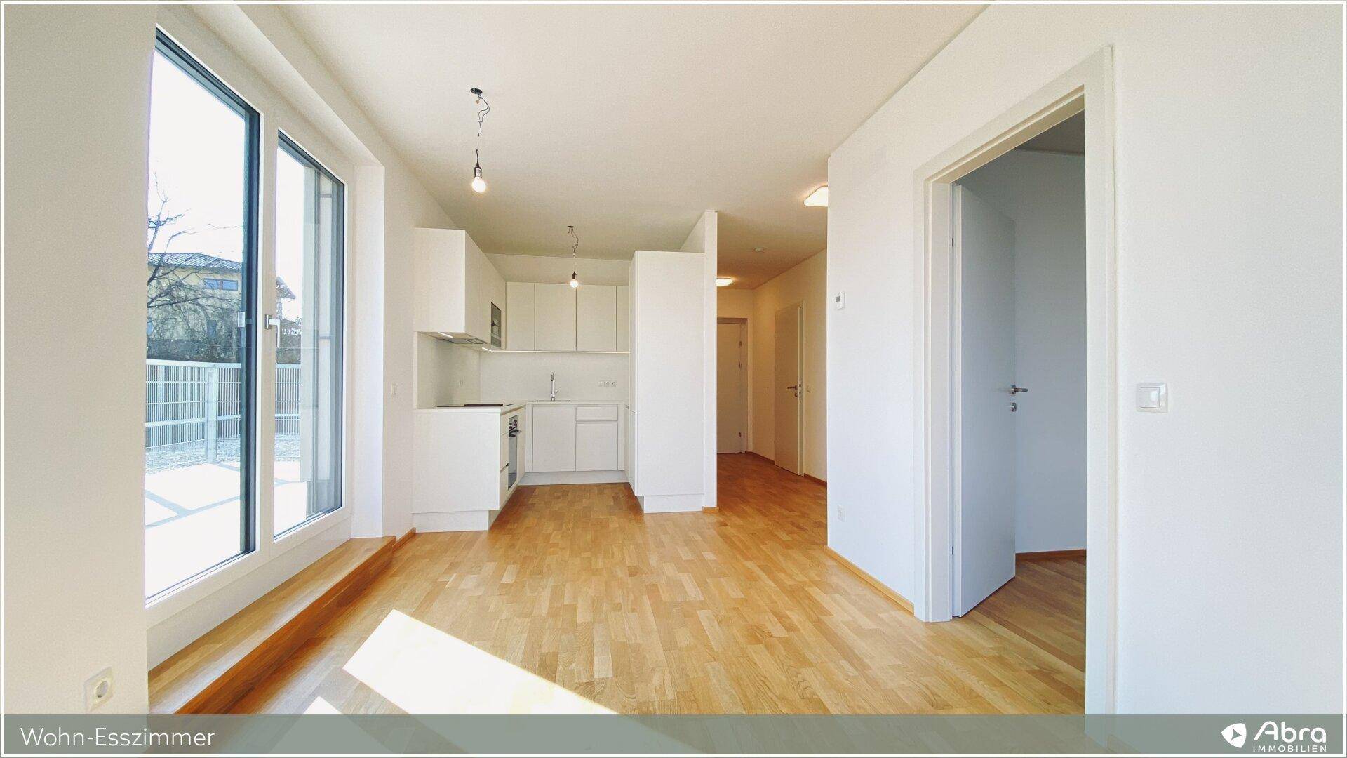 Offener Wohnbereich mit Parkettboden und Blick auf die moderne, integrierte Küche.