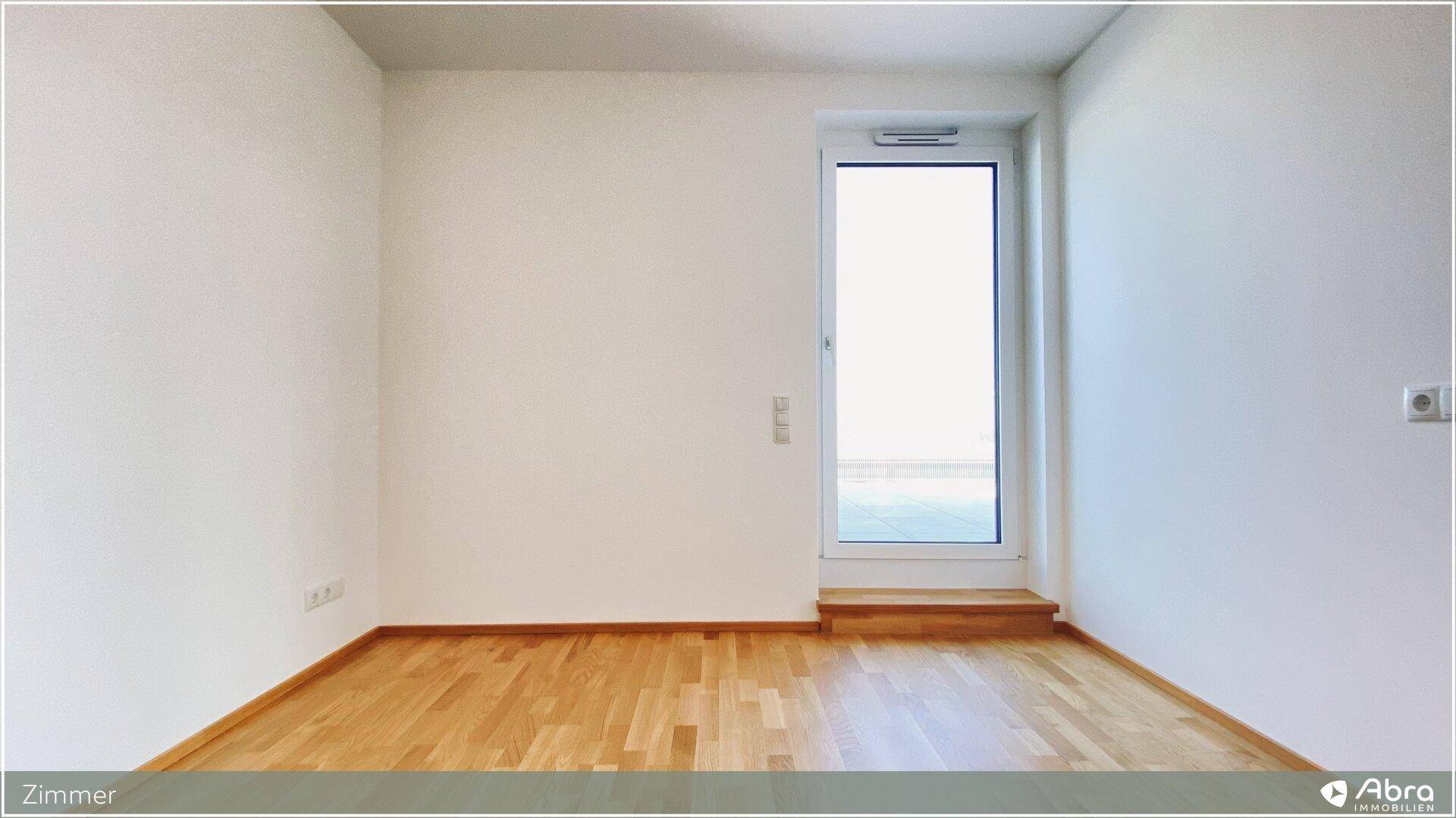 Helles Zimmer mit Parkettboden und Zugang zu einem Außenbereich, ideal als Schlafzimmer.