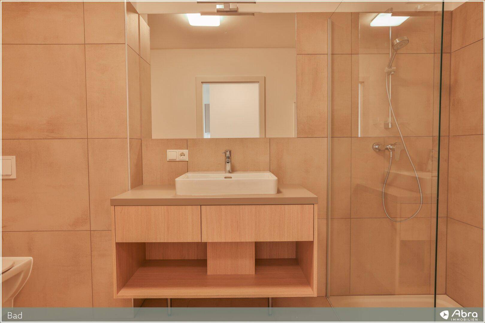 Funktionales Badezimmer mit modernem Waschtisch, großem Spiegel und Duschbereich.