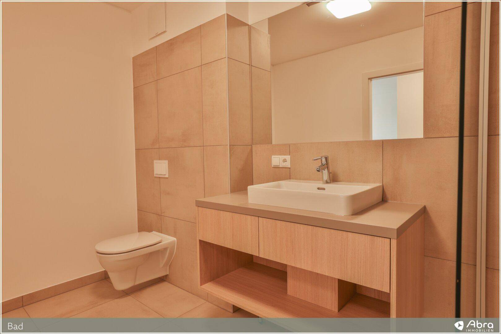 Gepflegtes Badezimmer mit wandhängendem WC, Waschtisch und beigefarbenen Fliesen.