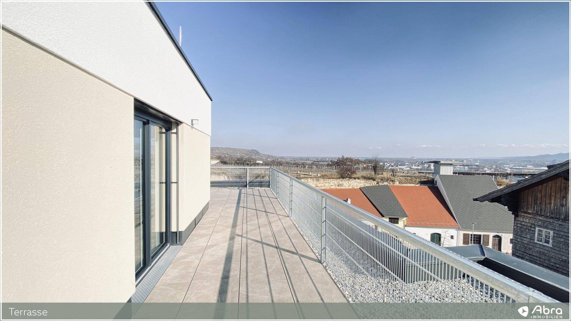 Helle Terrasse mit modernem Geländer und weitem Blick über die Dächer und Landschaft.