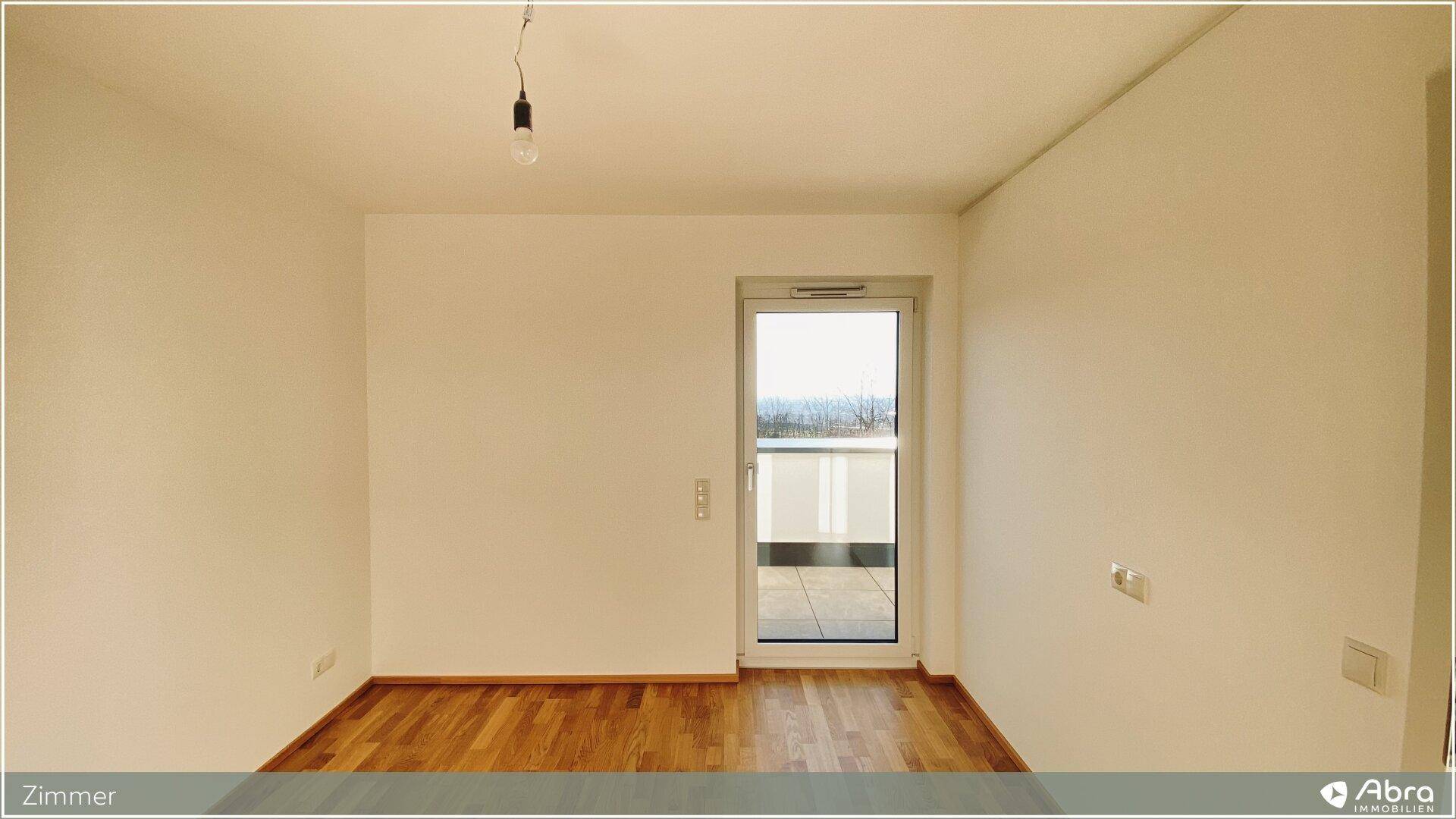 Helles Zimmer mit Parkettboden und Zugang zu einem Außenbereich, ideal als Schlaf- oder Arbeitszimmer.