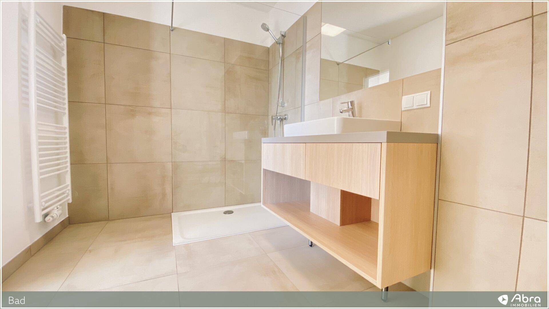 Modernes Badezimmer mit beigefarbenen Fliesen, begehbarer Dusche und stilvollem Waschtisch mit Einzelwaschbecken.