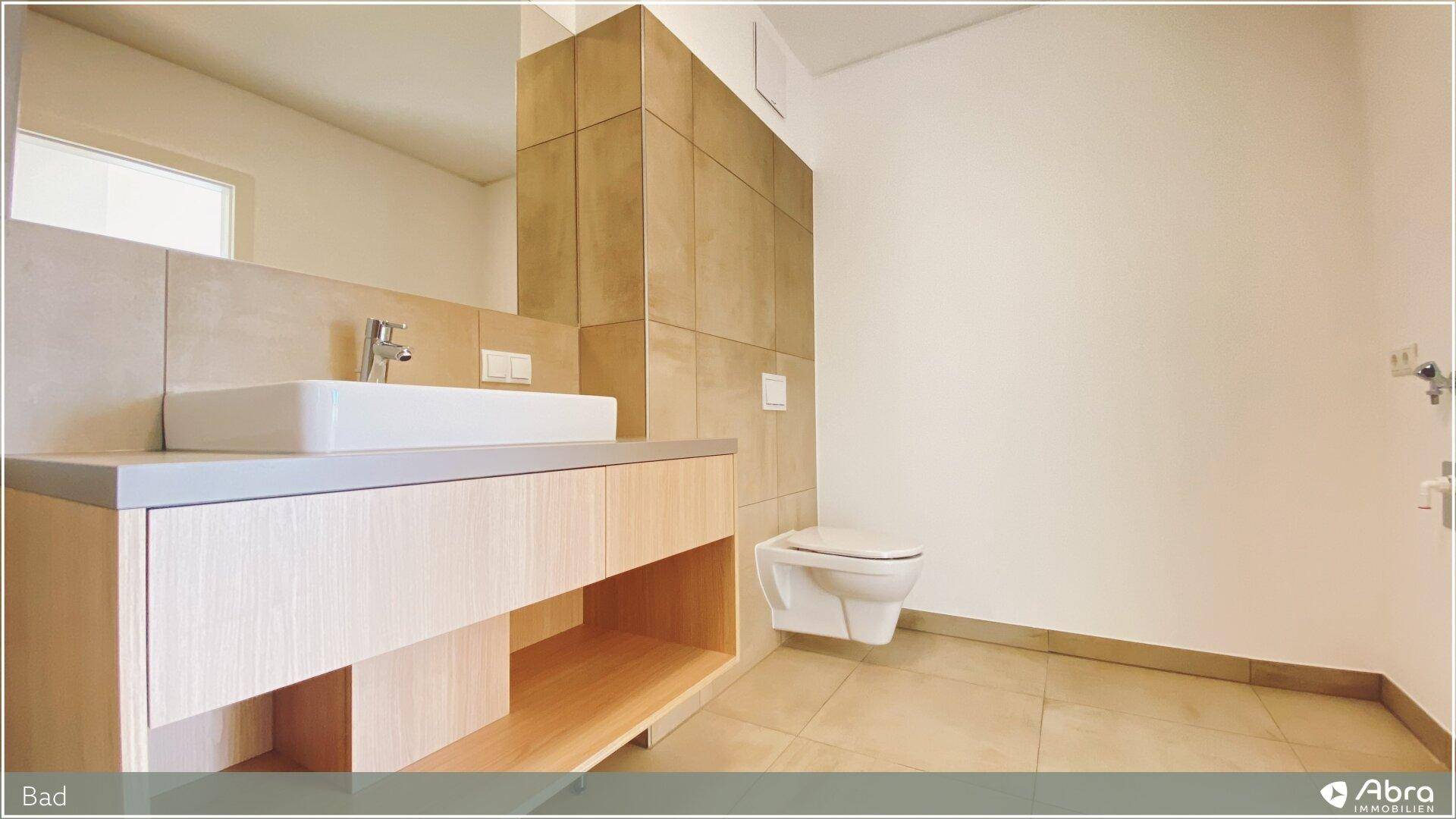 Modernes Badezimmer mit wandhängendem WC und elegantem Waschtisch, in hellen Beigetönen gehalten.
