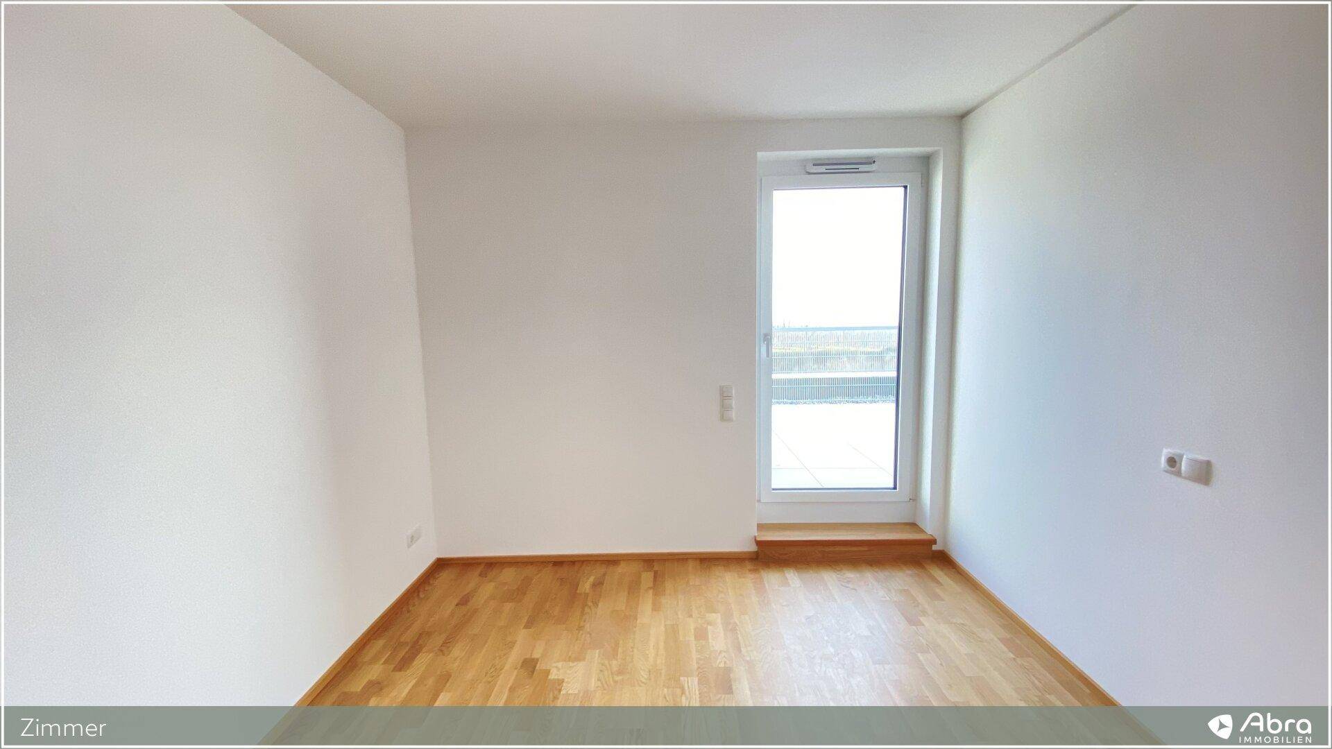 Helles Zimmer mit Holzboden und einem Fenster, das viel Tageslicht hereinlässt.