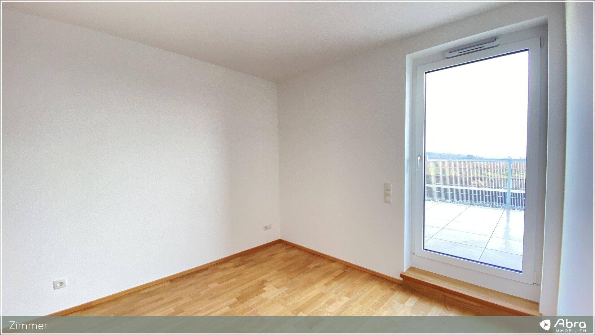 Geräumiges Zimmer mit Holzboden und direktem Zugang zu einer sonnigen Terrasse.