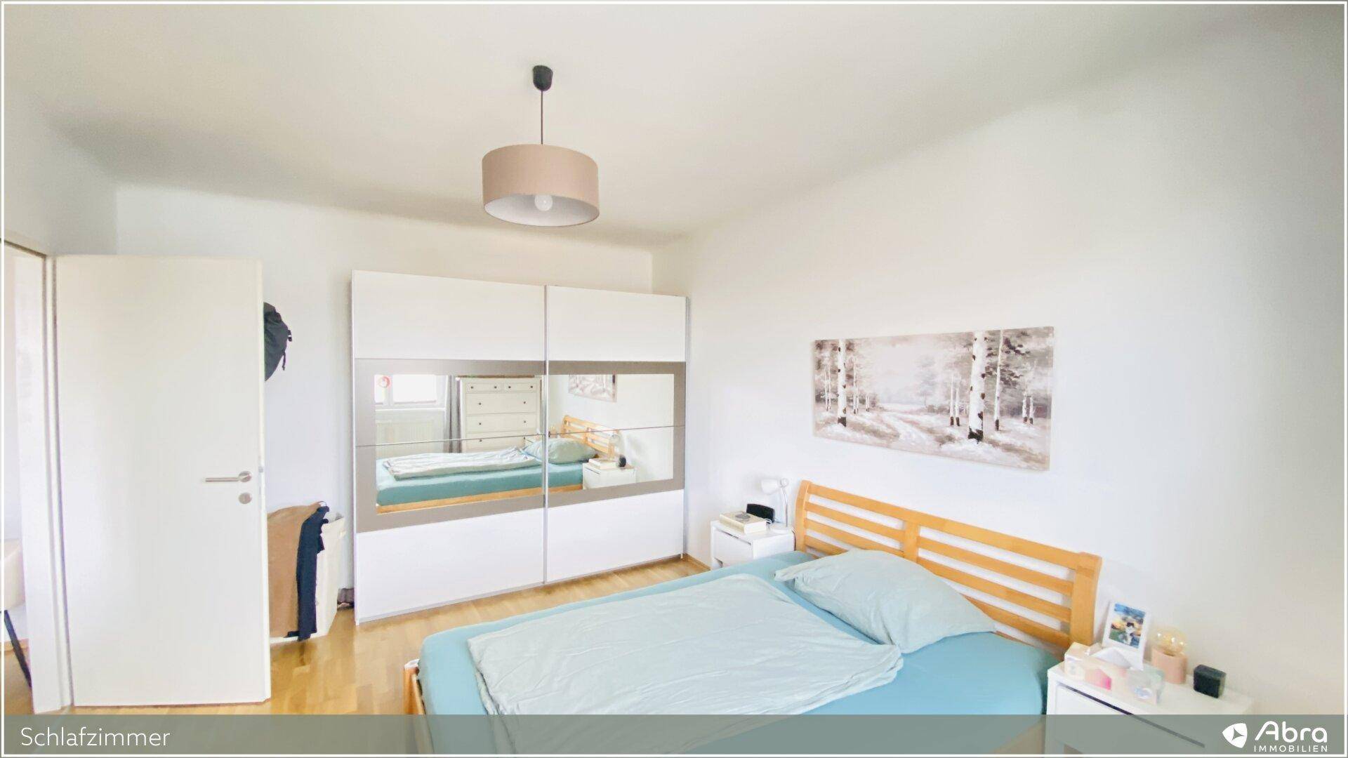 Schlafzimmer mit Holzbett, Spiegelschrank und hellem Holzboden, bietet eine ruhige Rückzugsmöglichkeit.