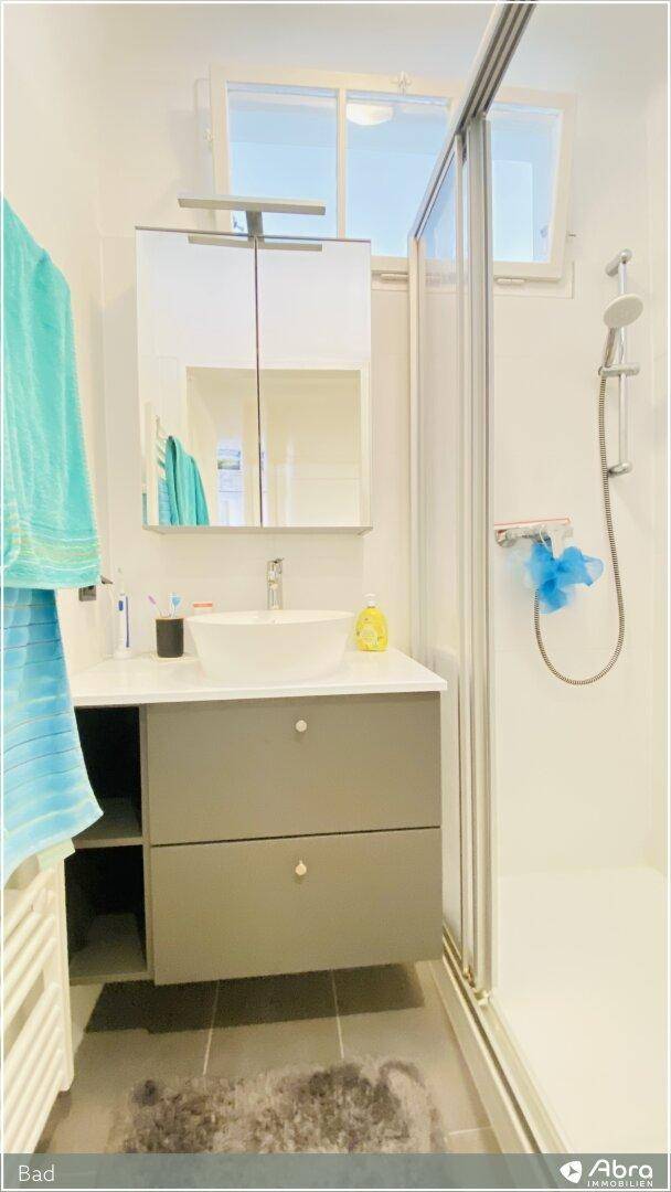 Modernes Badezimmer mit Dusche, Einzelwaschbecken und Spiegelschrank, hell und funktional.
