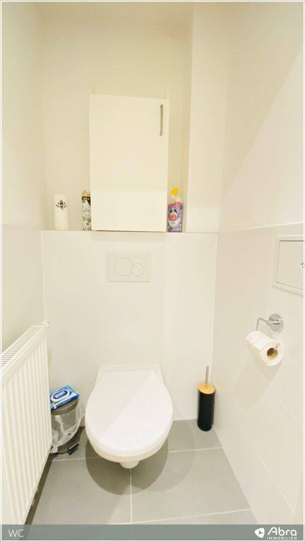 Separates WC mit wandhängender Toilette und kleinem Heizkörper, sauber und praktisch.
