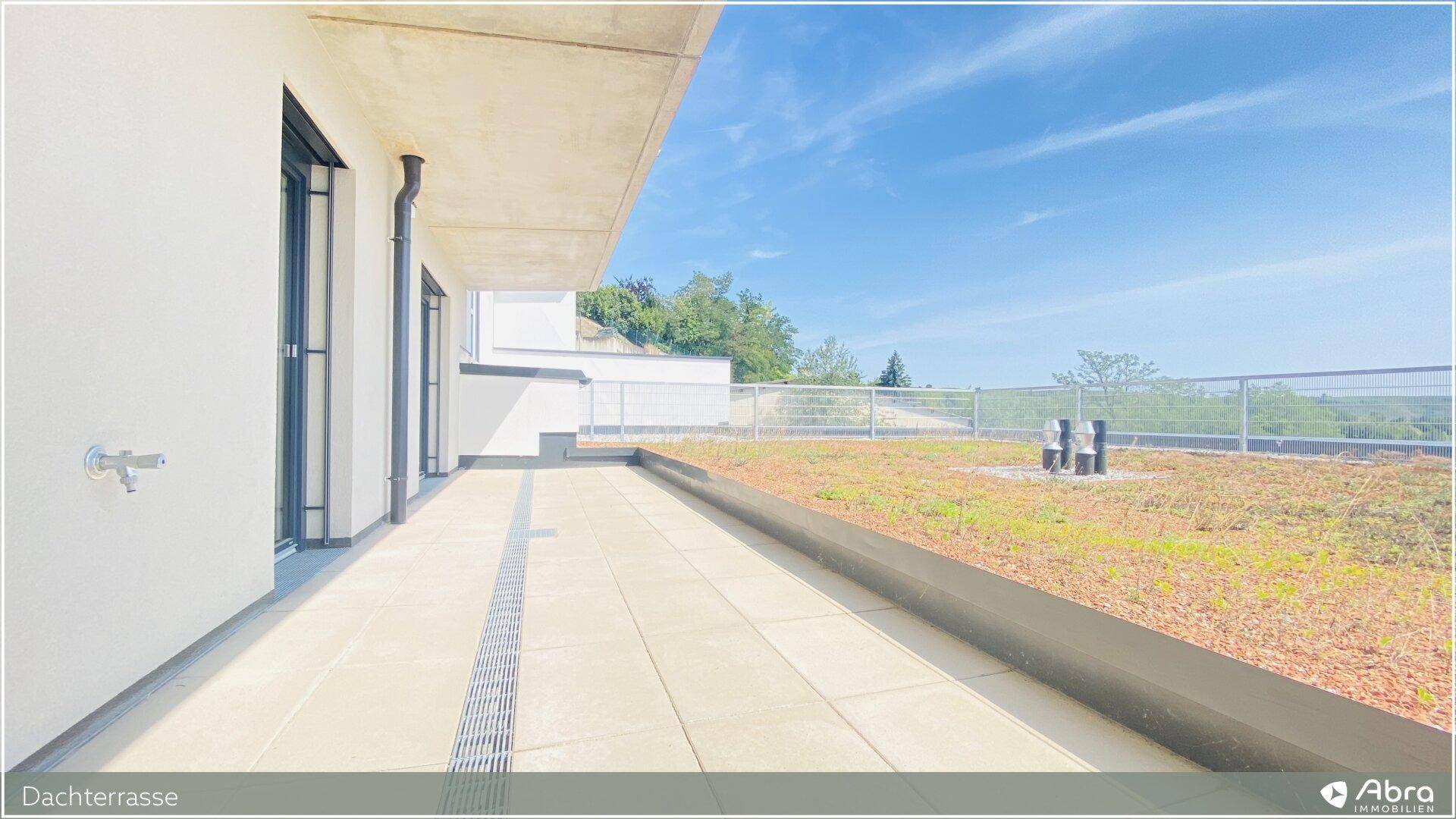 Sonnige Dachterrasse mit Fliesenboden und weitem Blick, ideal zum Entspannen im Freien.