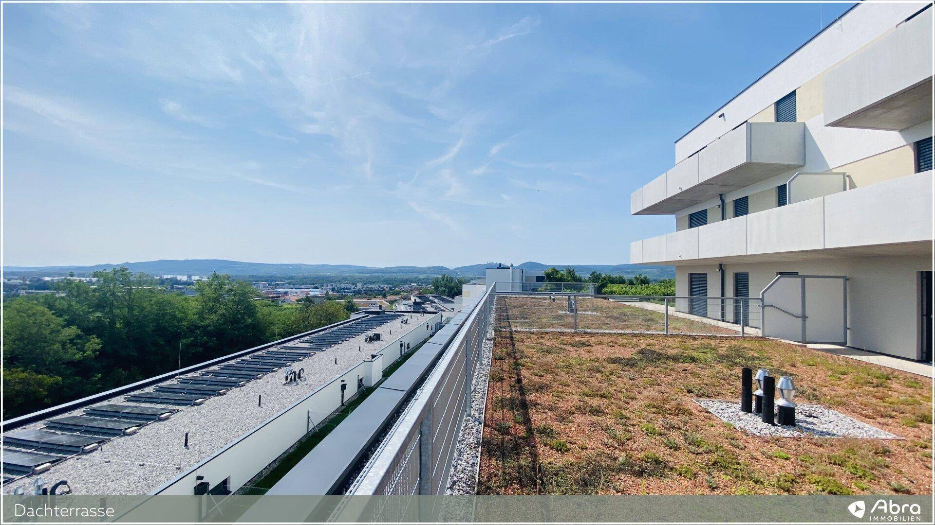 Moderne Wohnanlage mit mehreren Balkonen und Dachterrassen, eingebettet in die Natur.