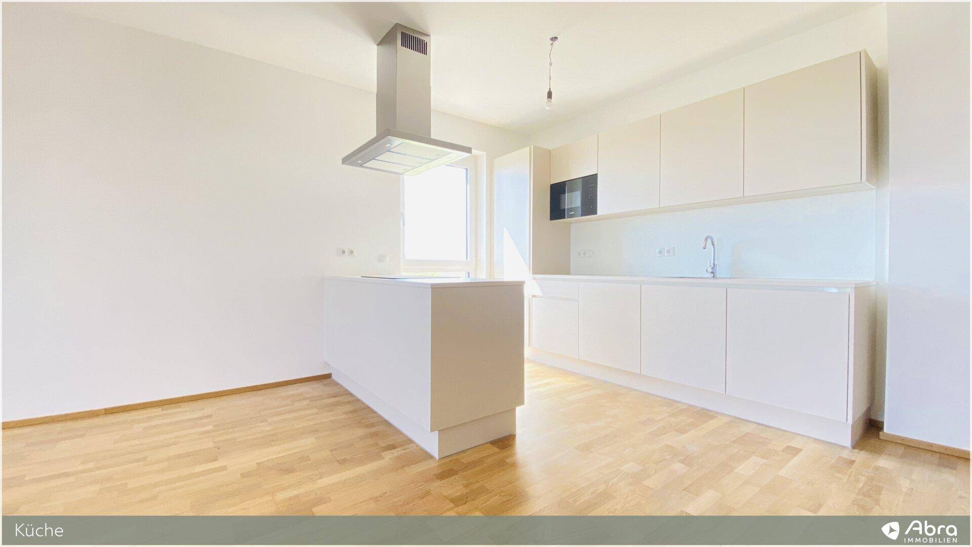 Moderne, unbenutzte Küche mit weißer Kücheninsel, Dunstabzugshaube und viel Stauraum.