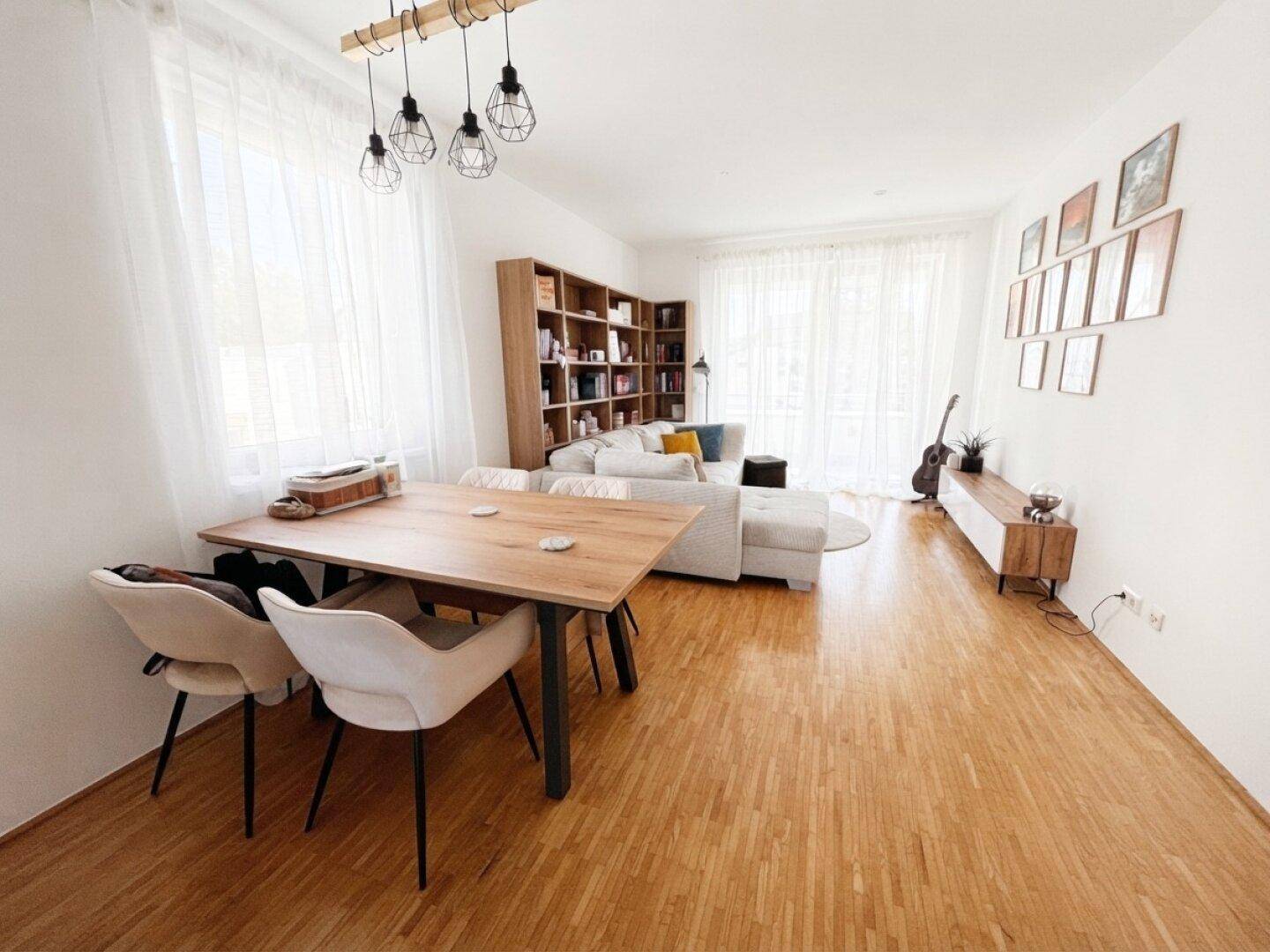 Geräumiger Wohn-Essbereich mit viel Tageslicht, Holzparkett und moderner Einrichtung.