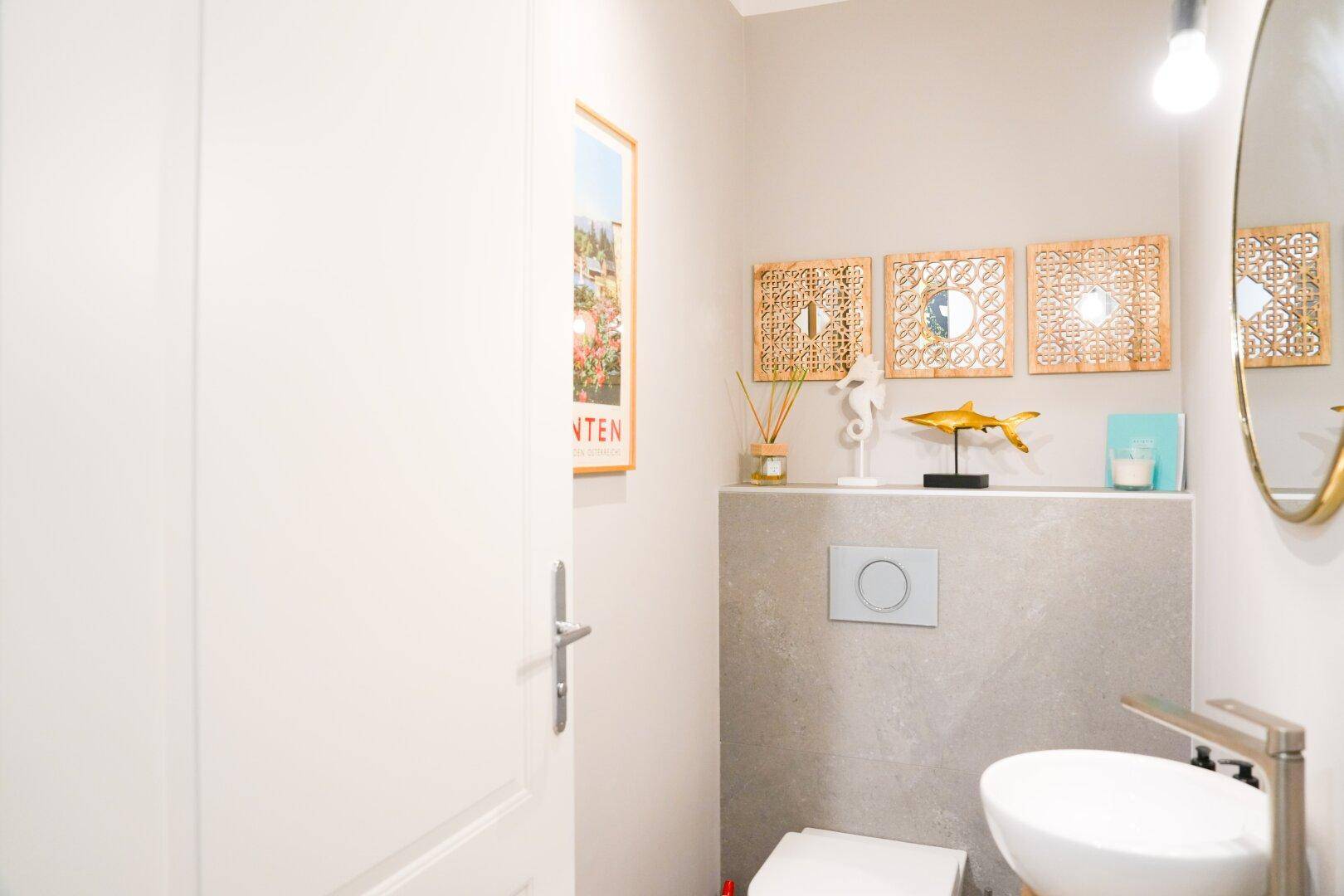 Modernes Gäste-WC mit Wand-WC, kleinem Waschbecken und dekorativen Elementen.