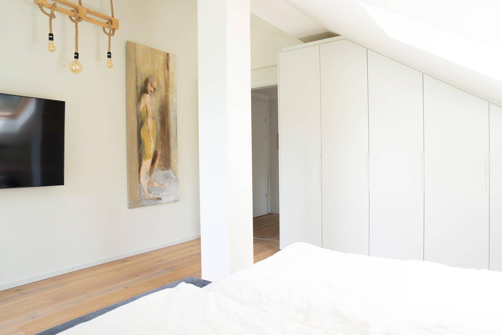 Helles Schlafzimmer im Dachgeschoss mit Einbauschränken und moderner Dekoration.