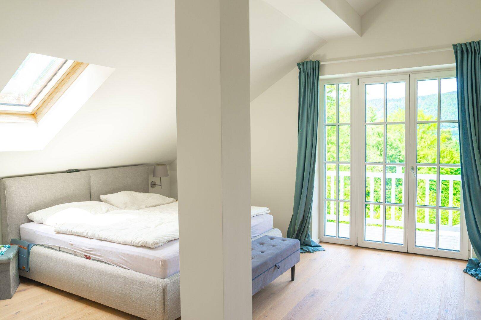 Geräumiges Schlafzimmer im Dachgeschoss mit Doppelbett, Dachfenster und Balkonzugang.