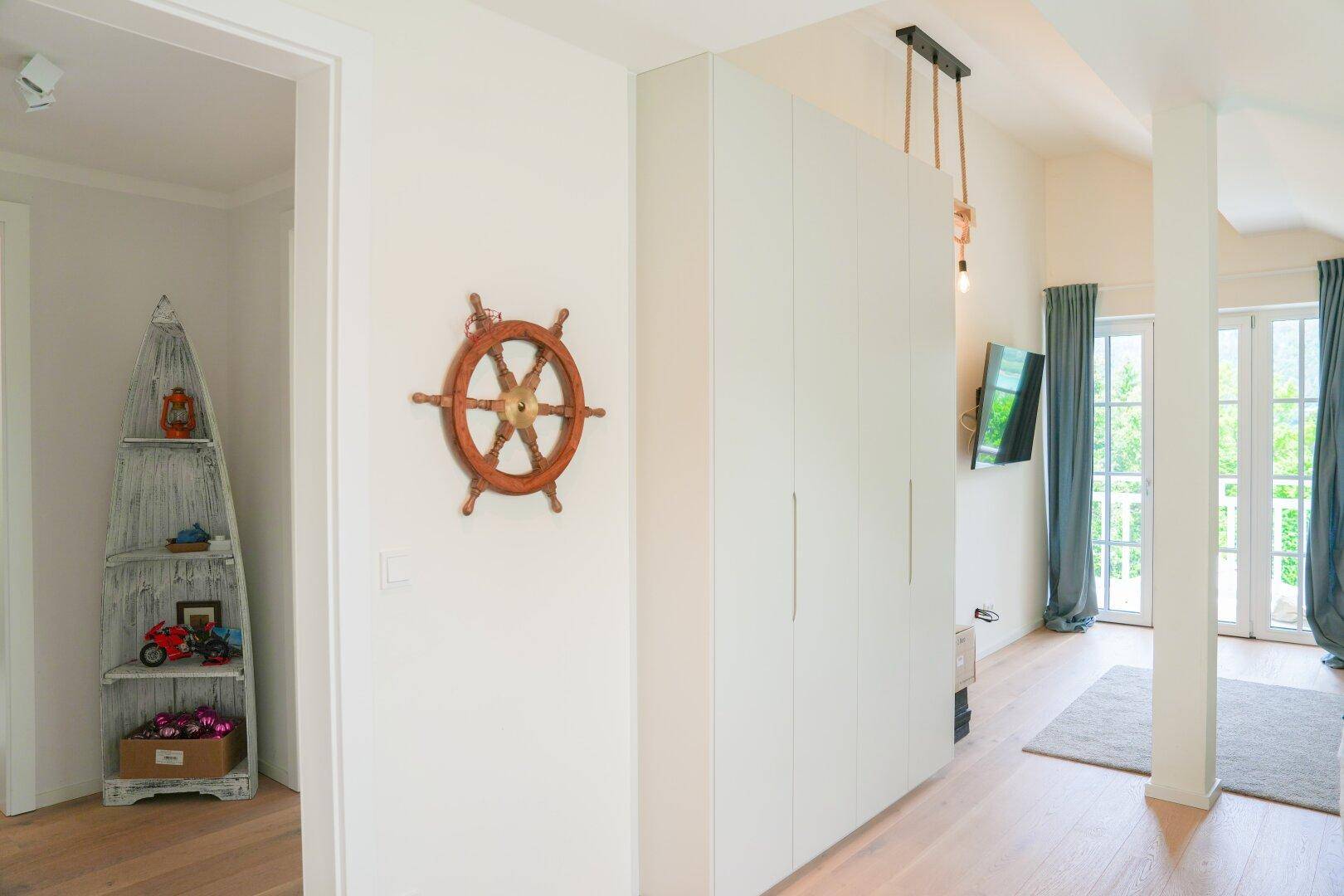 Heller Flur mit Einbauschränken und maritimer Dekoration, der zu einem Schlafzimmer führt.