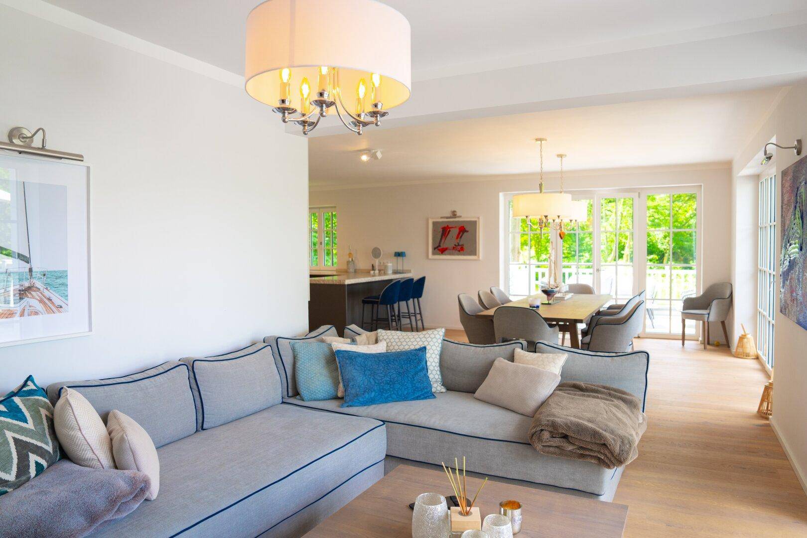 Offener Wohn-Essbereich mit Sofa, Esstisch und Blick auf die moderne Küche im Hintergrund.