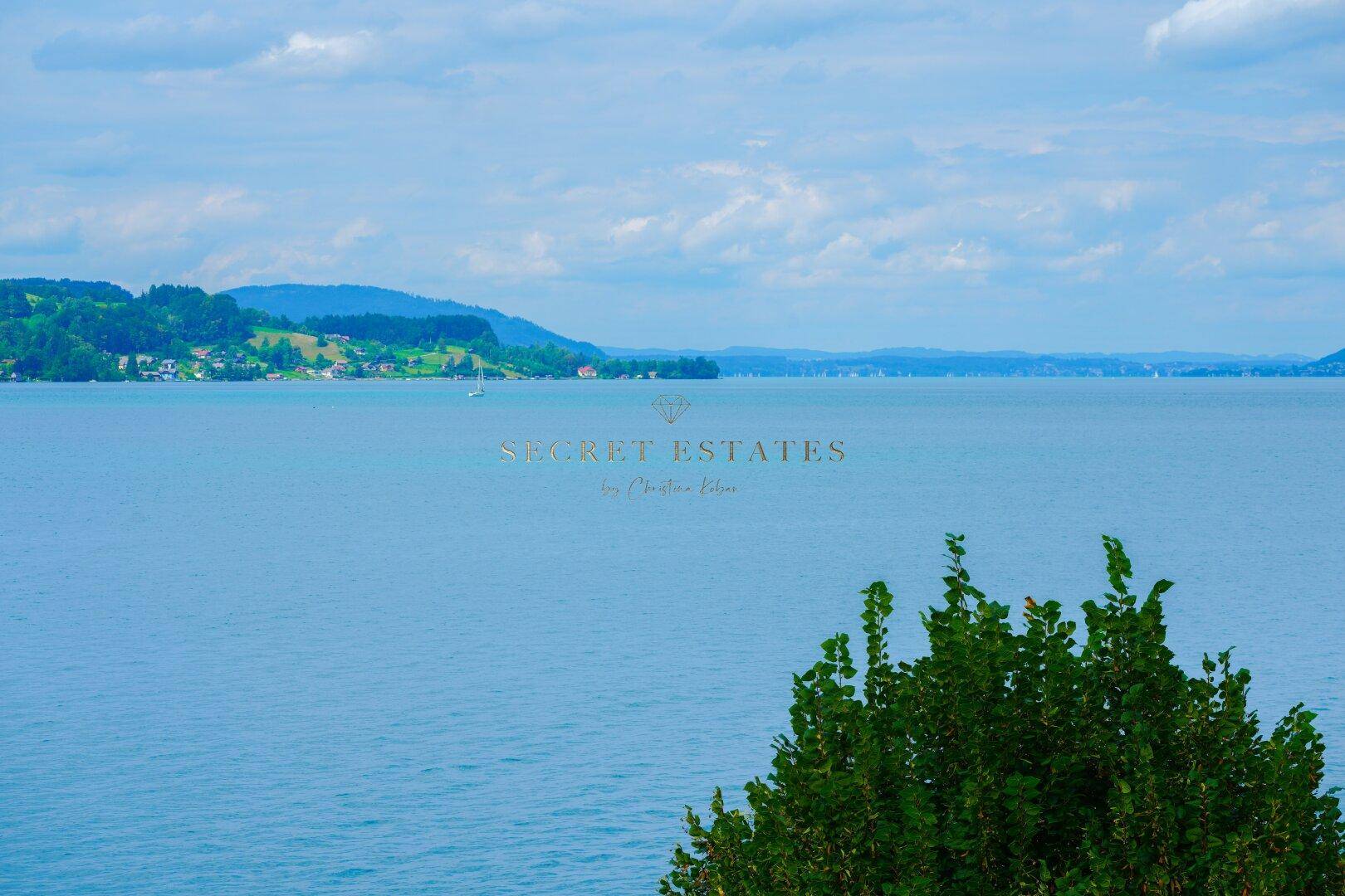 Weitläufiger Blick über den blauen See und die umliegende Berglandschaft.