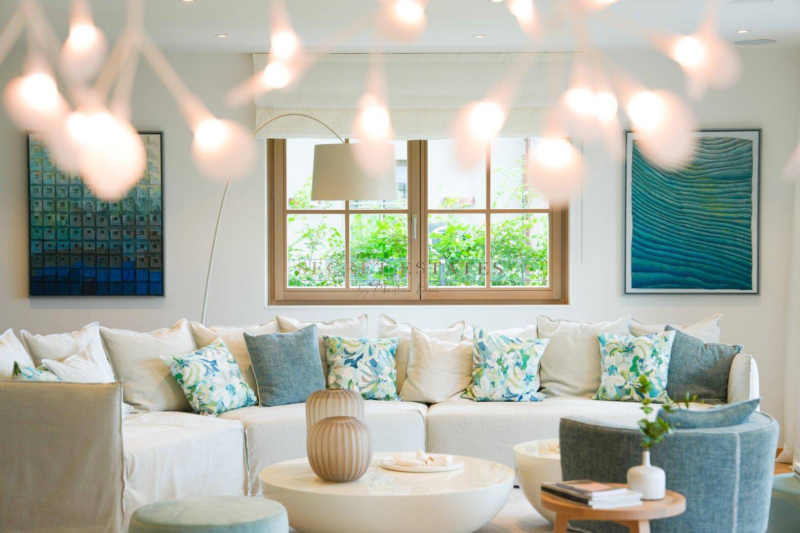 Gemütliches Wohnzimmer mit großem Sofa, vielen Kissen und Blick ins Grüne.