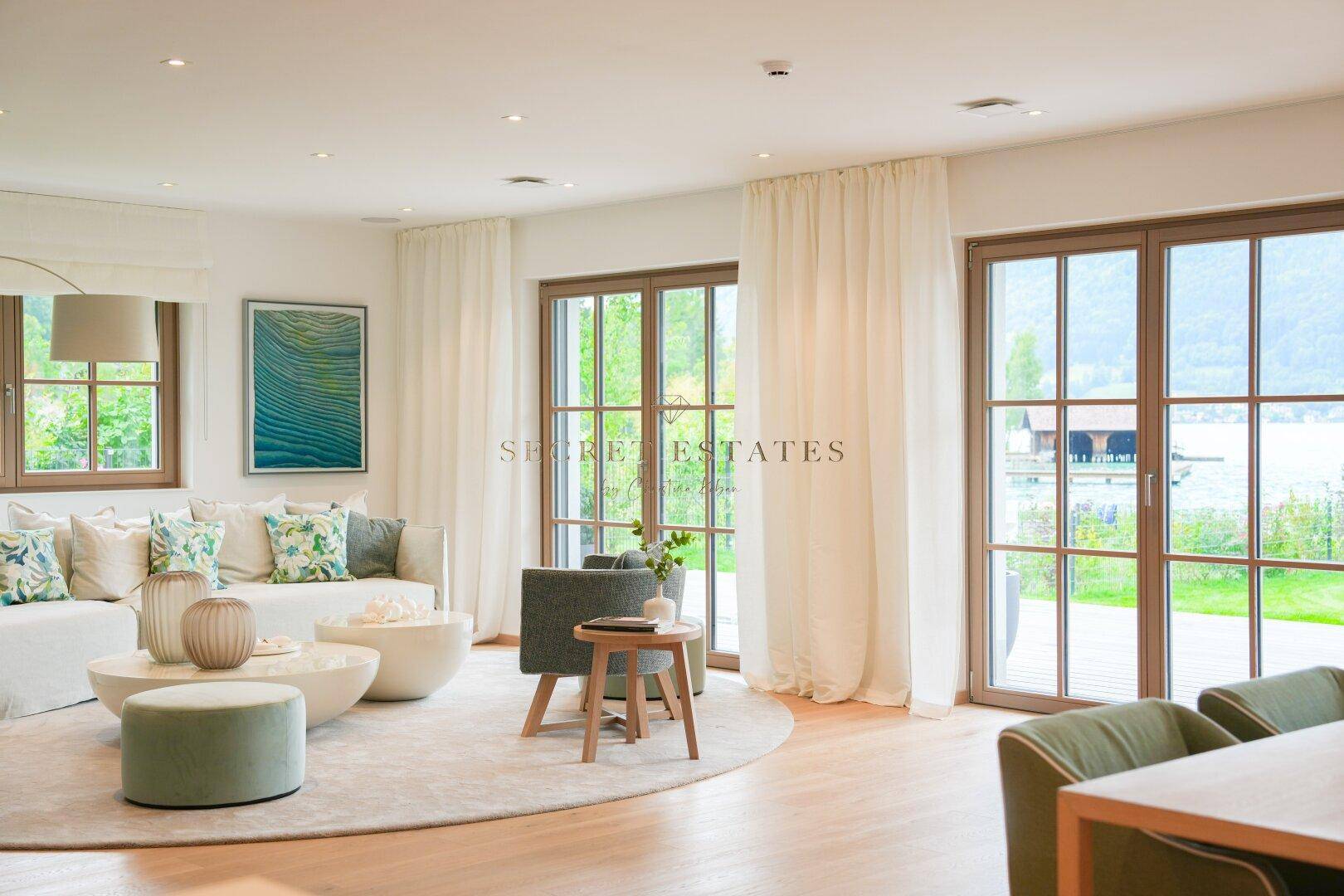 Helles Wohnzimmer mit Seeblick, Holzboden und Zugang zu den Außenterrassen.