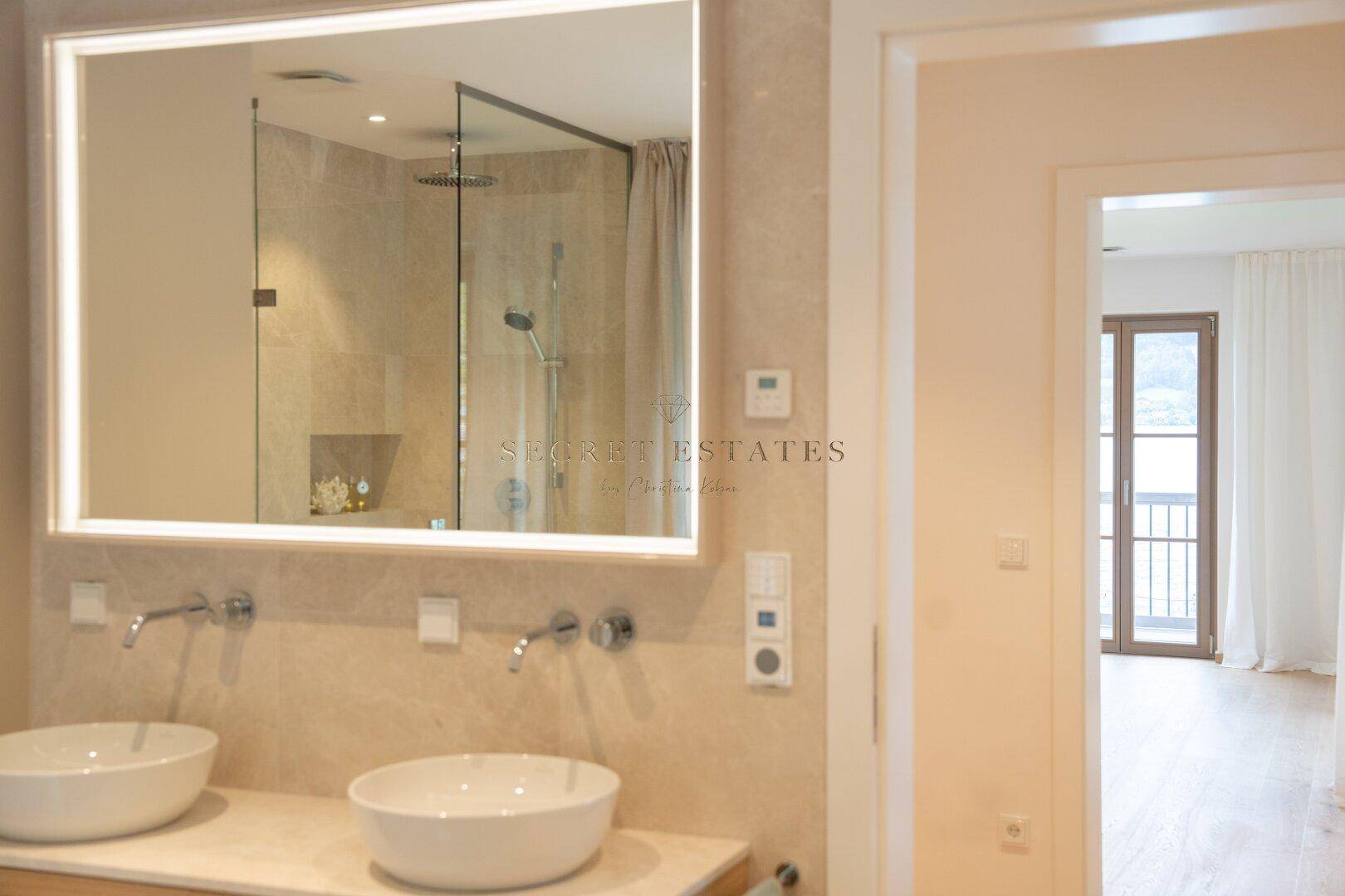 Modernes Badezimmer mit Doppelwaschbecken, großer Spiegelfläche und begehbarer Regendusche.