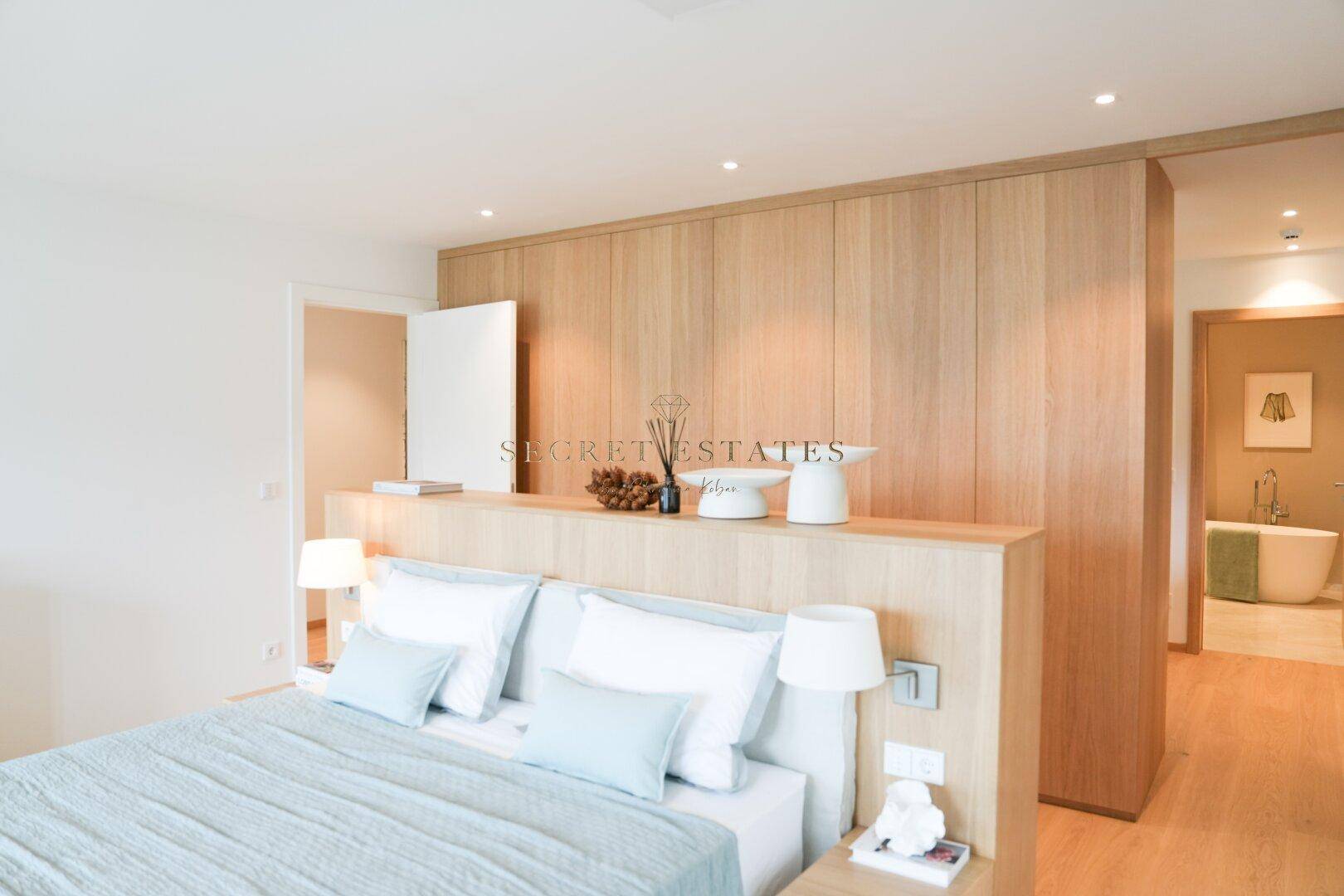 Schlafzimmer mit Holzelementen, Doppelbett und integriertem Badbereich.