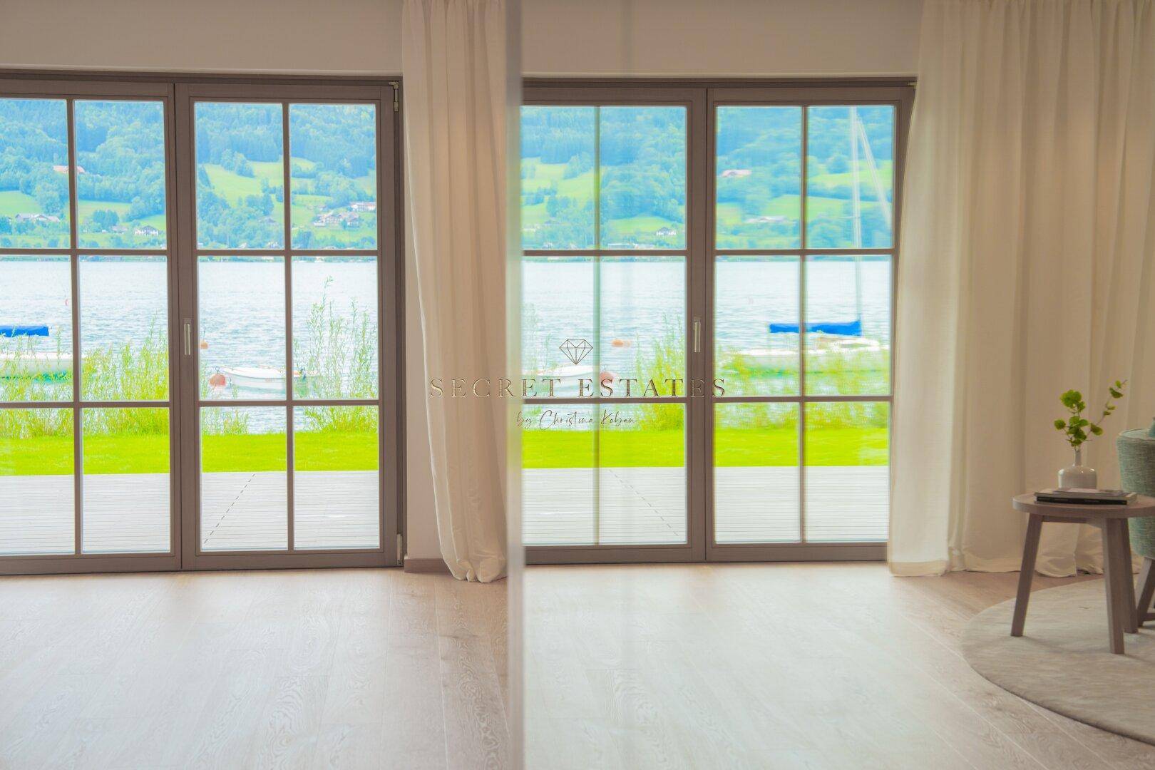 Große Fensterfronten bieten einen weiten Blick auf den See und die grüne Umgebung.