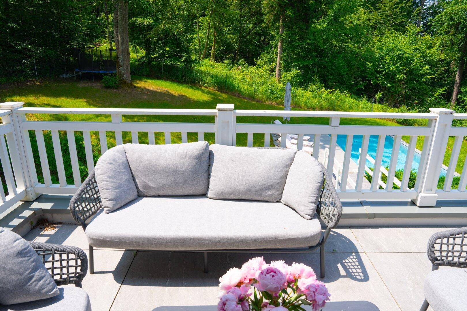 Sonnige Terrasse mit bequemer Sitzgelegenheit und Blick auf den privaten Poolbereich.