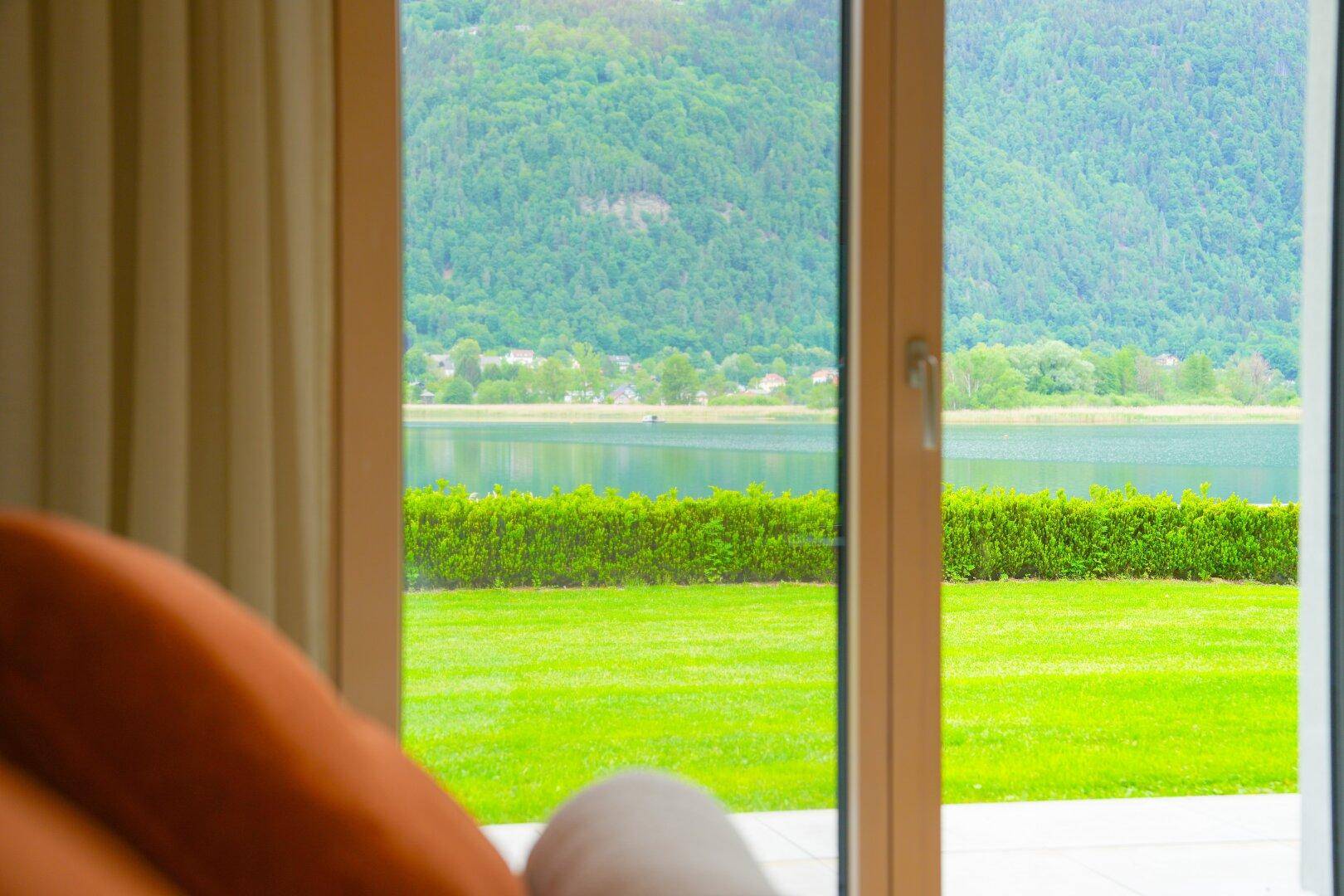Malerischer Blick auf den See und die umliegende grüne Landschaft durch das Fenster.