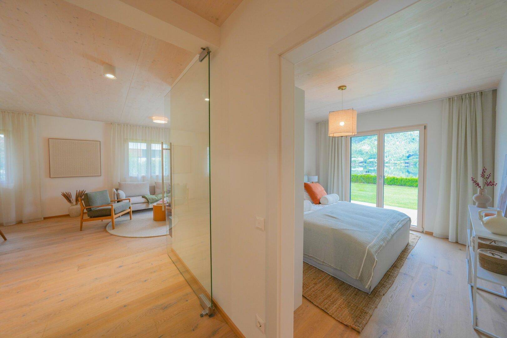 Übergangsbereich mit Glaswand zwischen Wohnzimmer und Schlafzimmer mit Gartenblick.