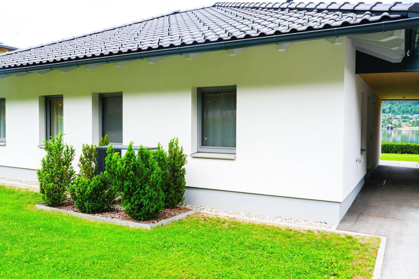 Seitenansicht eines modernen Hauses mit weißer Fassade und gepflegtem Vorgarten.