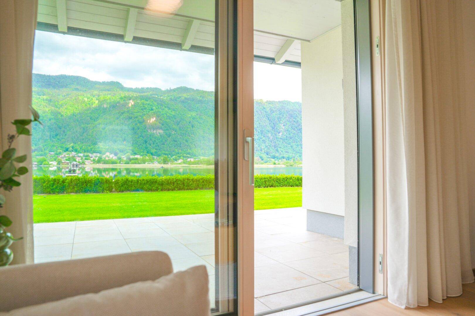 Große Schiebetüren bieten Zugang zur Terrasse mit weitem Blick auf den See und die Berge.