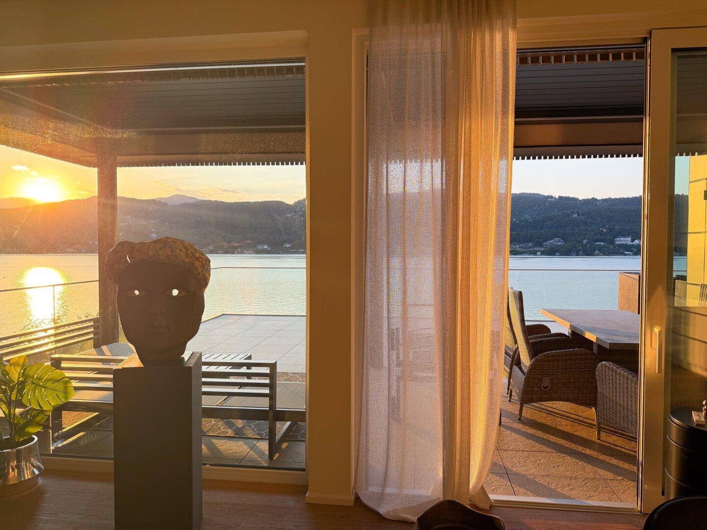 Heller Wohnbereich mit großen Fenstern, die einen atemberaubenden Seeblick und Zugang zur Terrasse bieten.