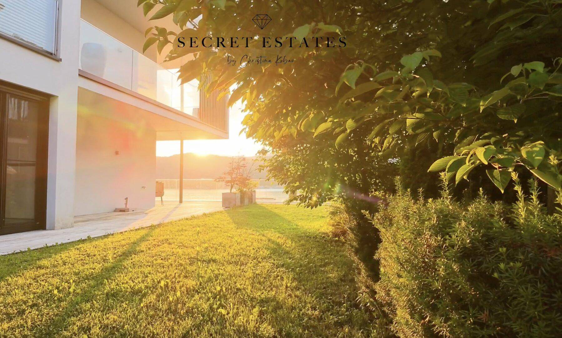 Moderne Architektur mit gepflegtem Rasen und atemberaubendem Blick auf den See bei Sonnenuntergang.
