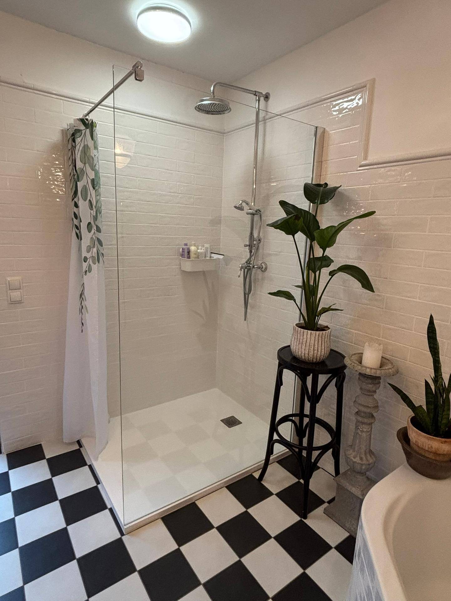 Moderne Dusche mit Glaswand, Regendusche und schwarz-weißem Fliesenboden im Badezimmer.