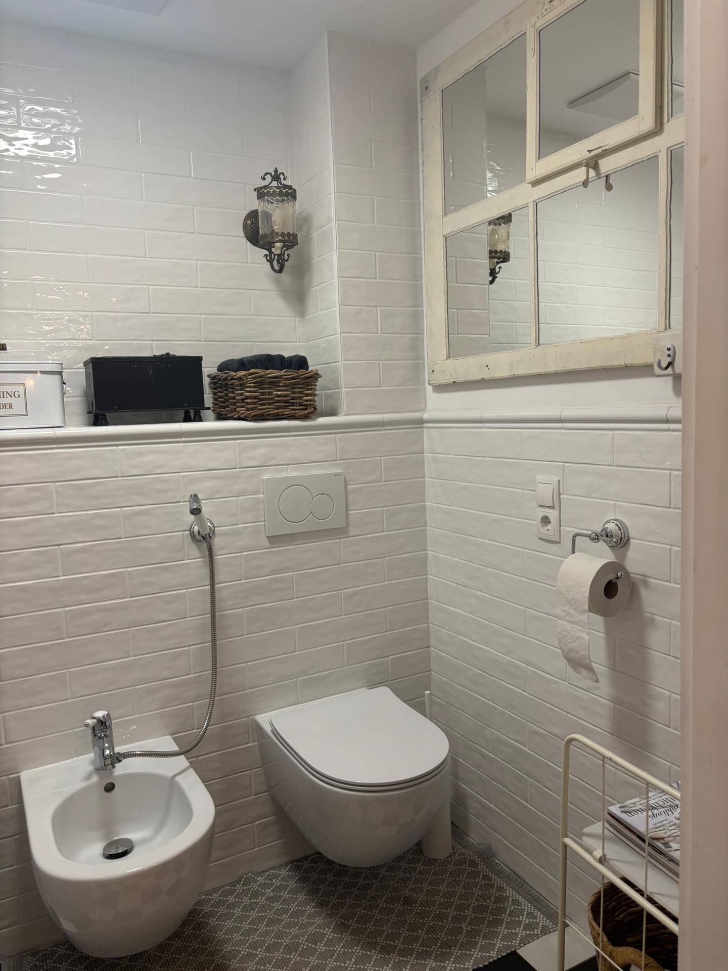 Modernes Gäste-WC mit Bidet, wandhängendem WC und weißen Fliesen an den Wänden.
