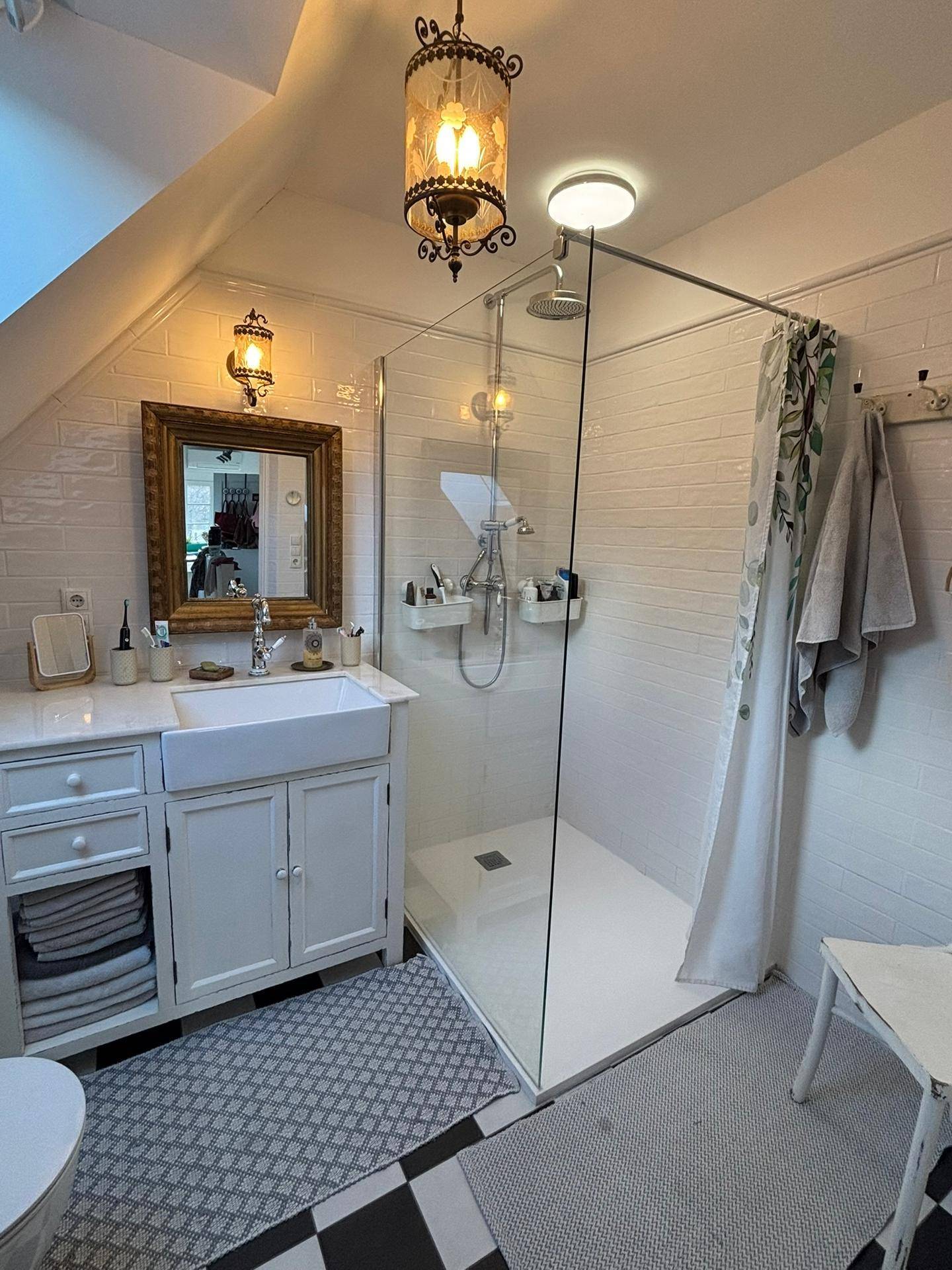 Modernes Badezimmer im Dachgeschoss mit Dusche, Waschbecken und Dachfenster.