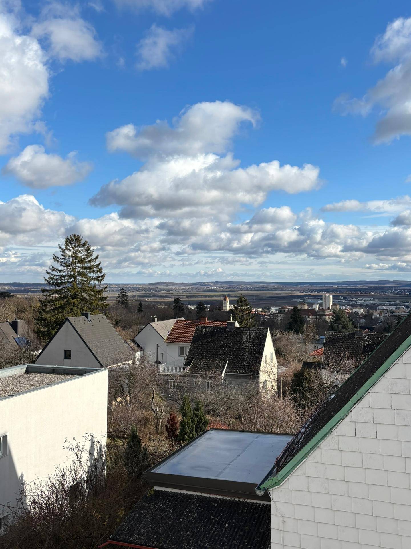 Weiter Ausblick über die Dächer der Stadt und die umliegende Landschaft an einem sonnigen Tag.