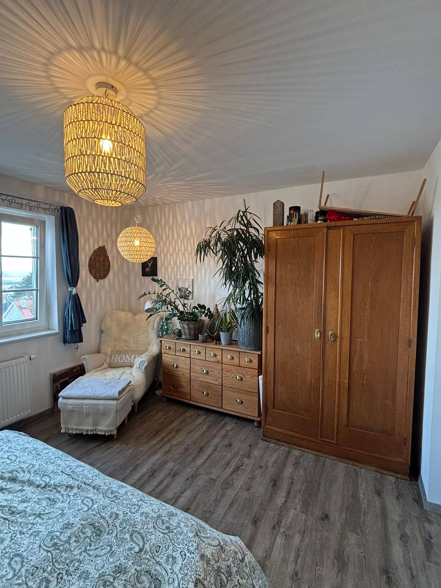 Gemütliches Schlafzimmer mit Holzboden, großem Kleiderschrank und Pflanzen.