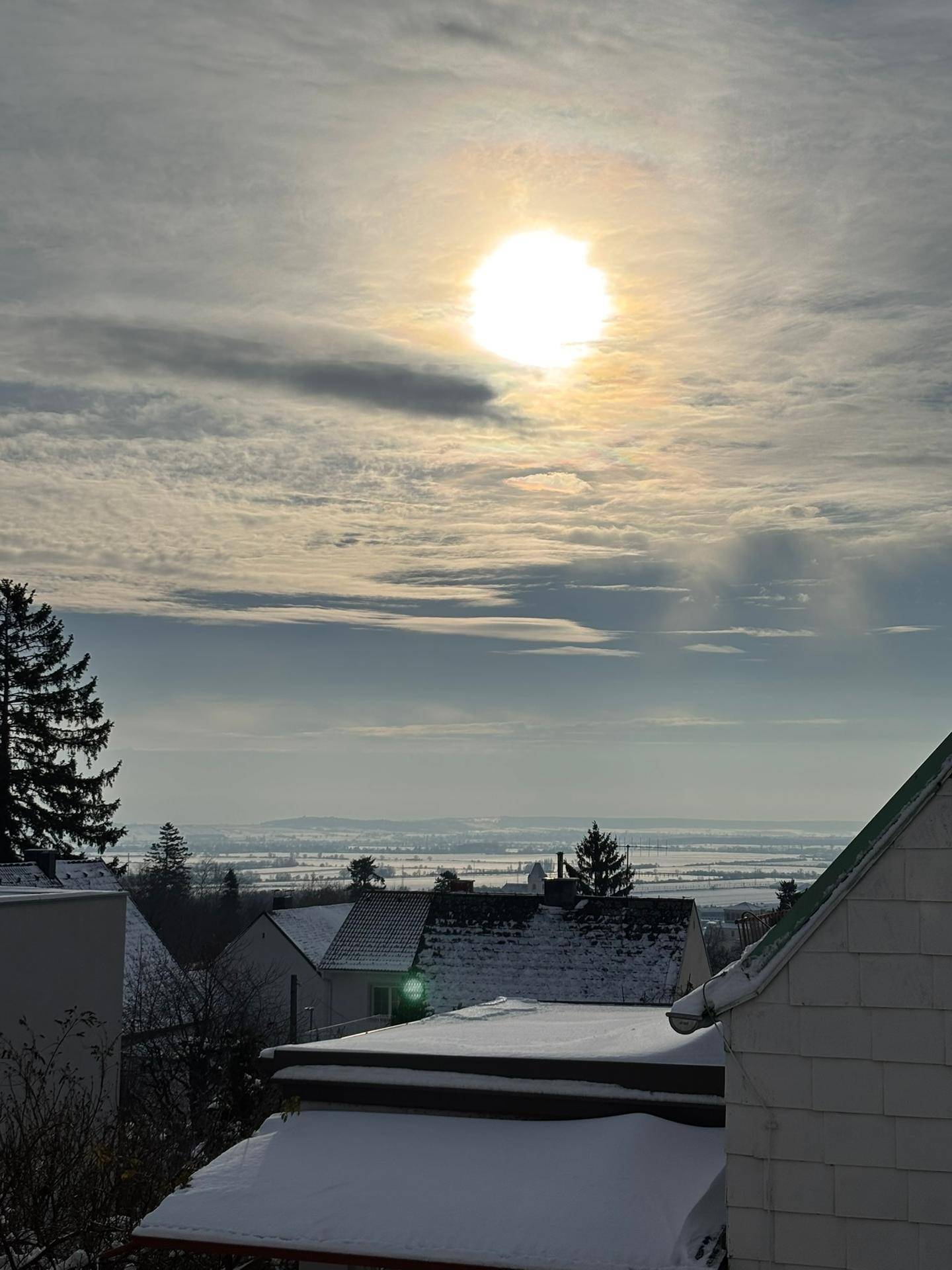Winterlicher Ausblick über die Dächer der Umgebung mit strahlender Sonne und weitem Horizont.