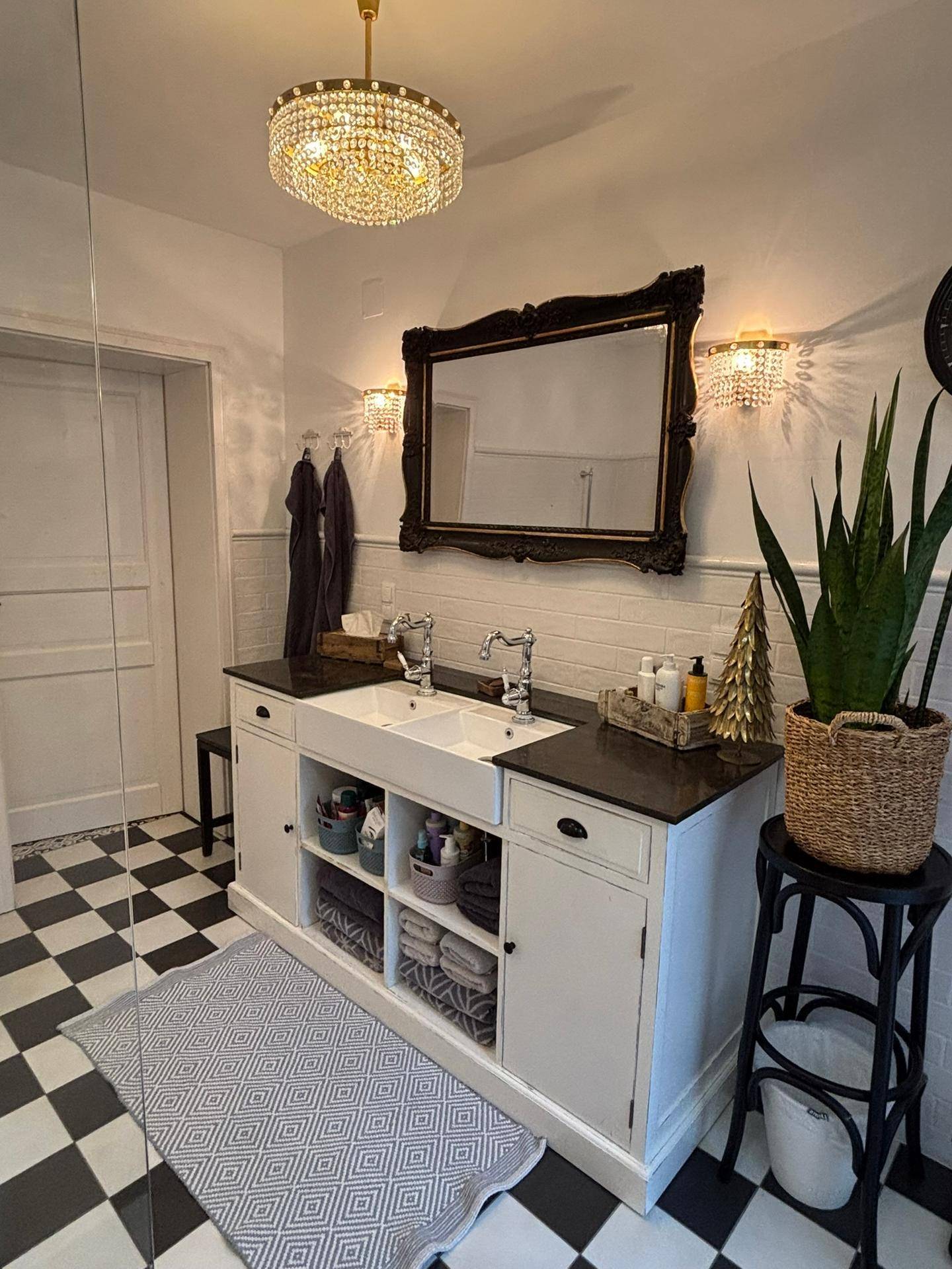 Geräumiges Badezimmer mit Doppelwaschbecken, großer Spiegelschrank und schwarz-weißem Fliesenboden.