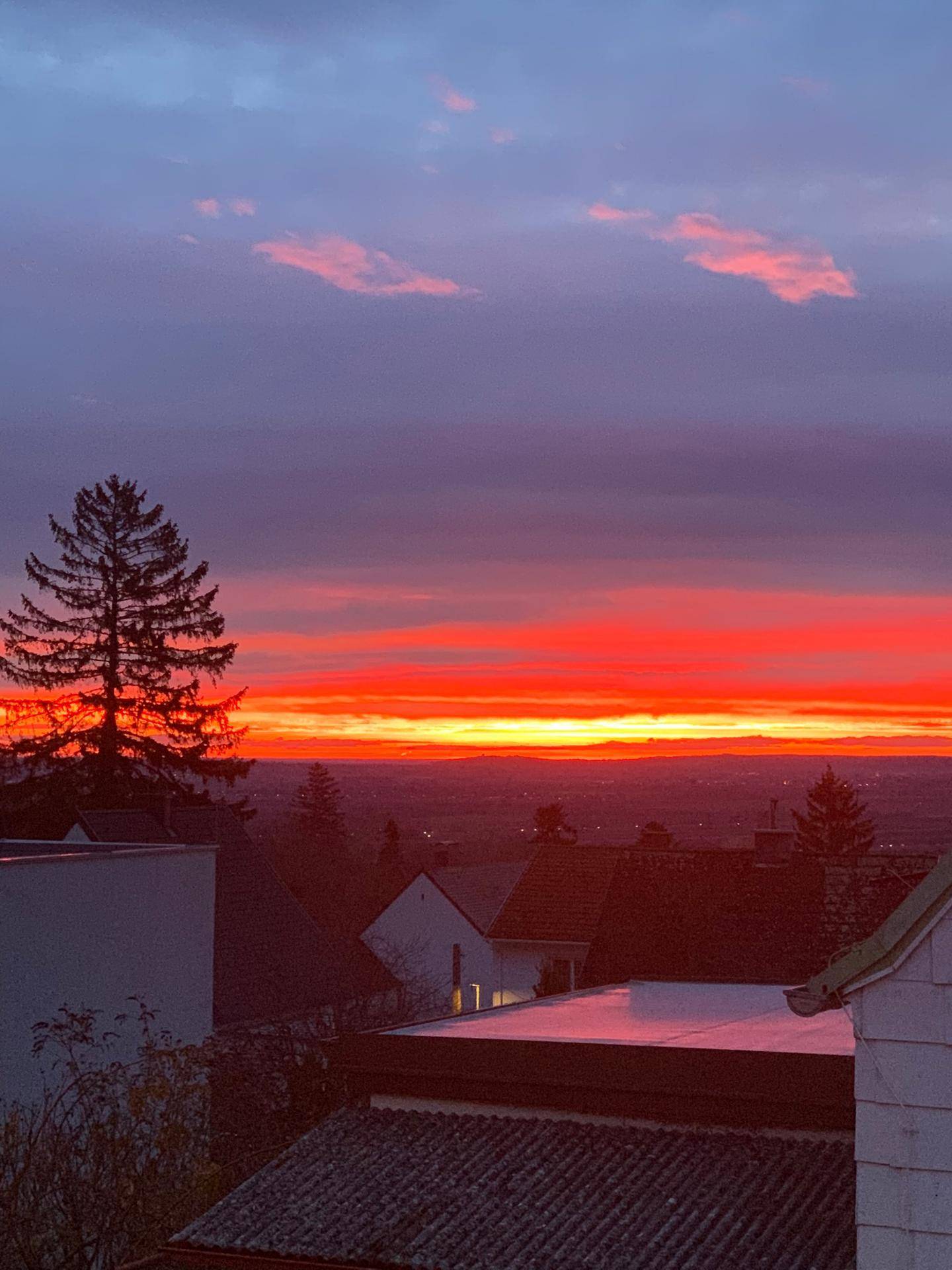 Spektakulärer Sonnenuntergang über der Landschaft mit leuchtend rotem Himmel und dunklen Silhouetten.