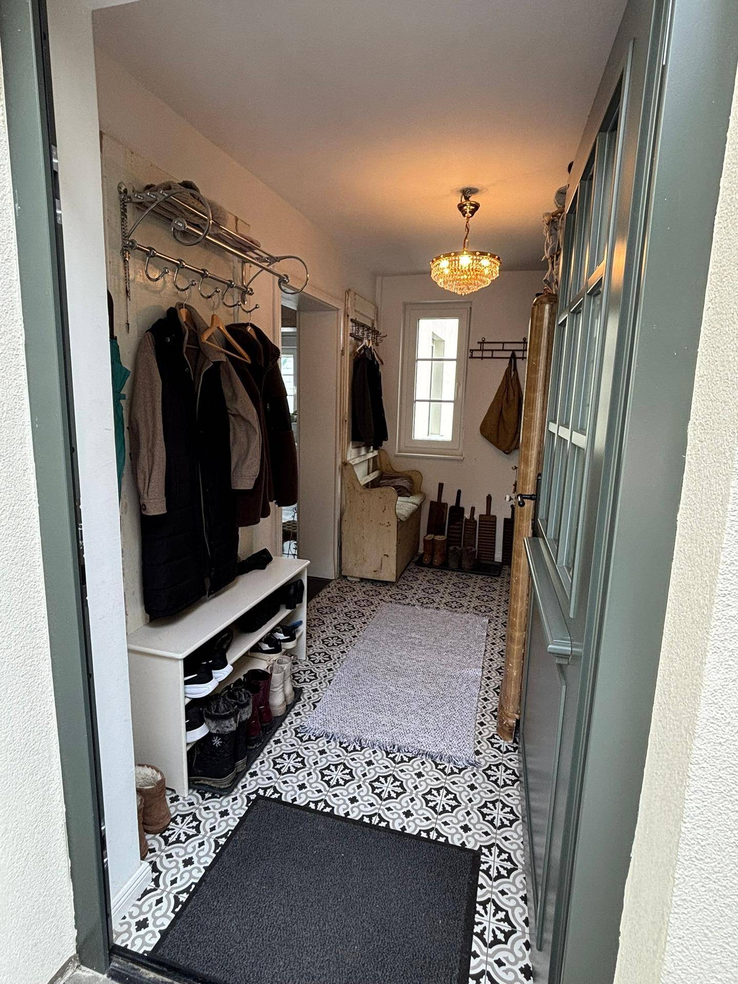 Heller Eingangsbereich mit gemusterten Fliesen, Garderobe und einem kleinen Fenster.