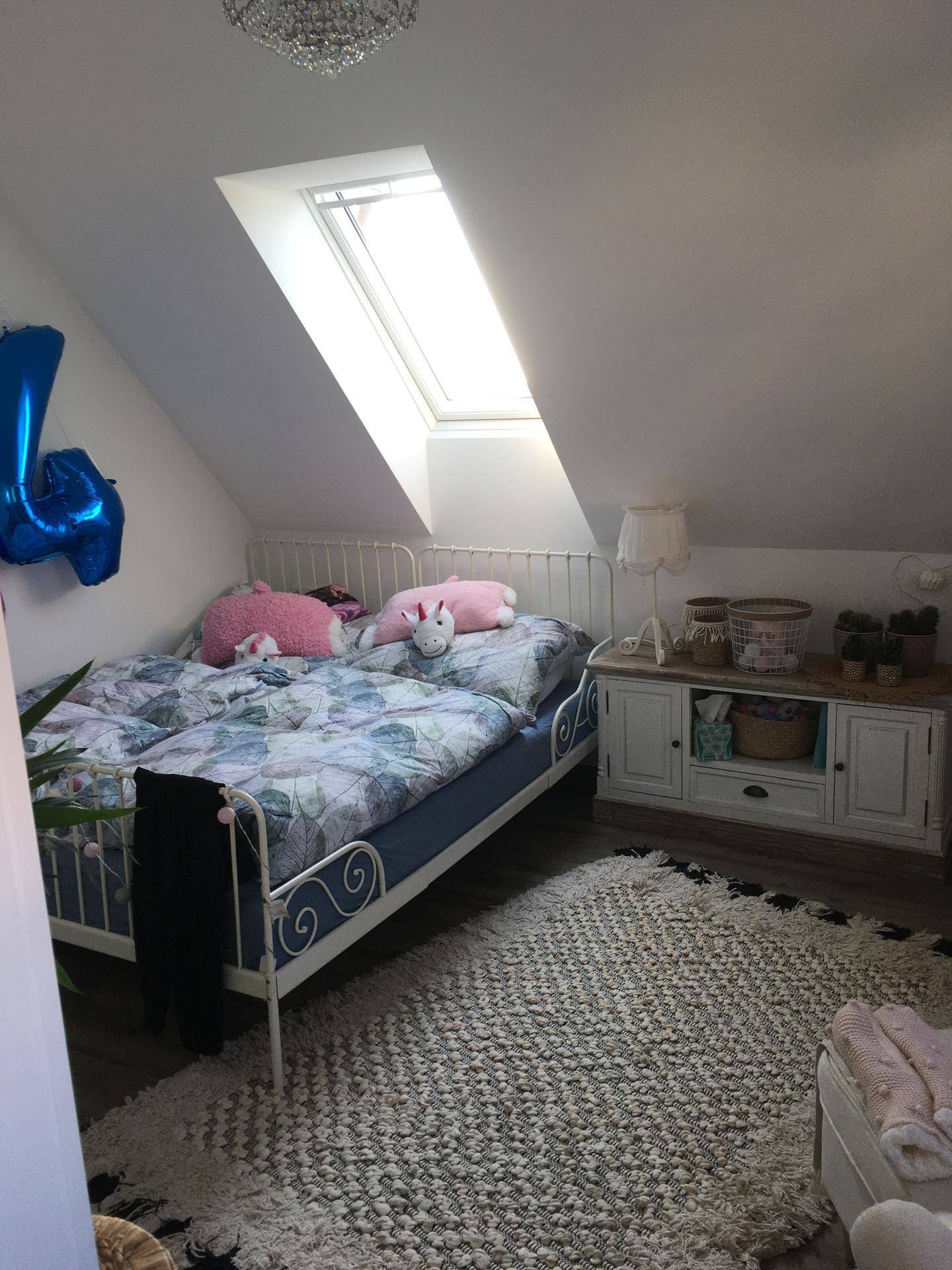 Kinderzimmer im Dachgeschoss mit zwei Betten, Teppich und Dachfenster.
