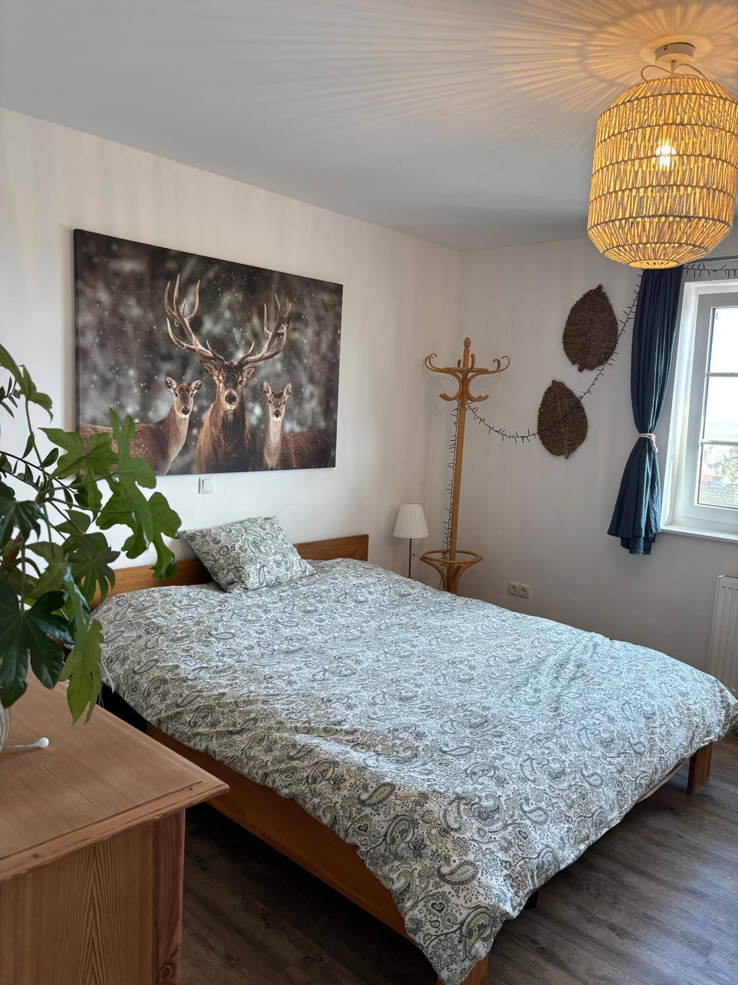 Helles Schlafzimmer mit Doppelbett, Holzboden und Fenster mit Ausblick.