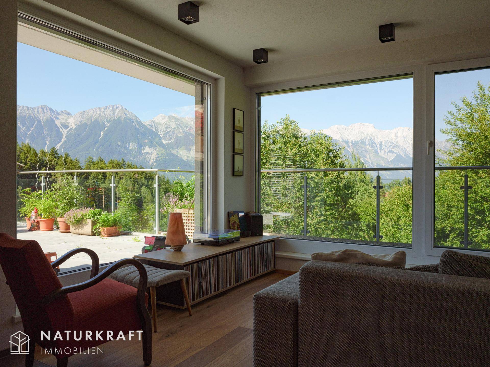 Helles Wohnzimmer mit großen Fenstern, die einen weiten Blick auf die Berge und die umliegende Natur bieten.