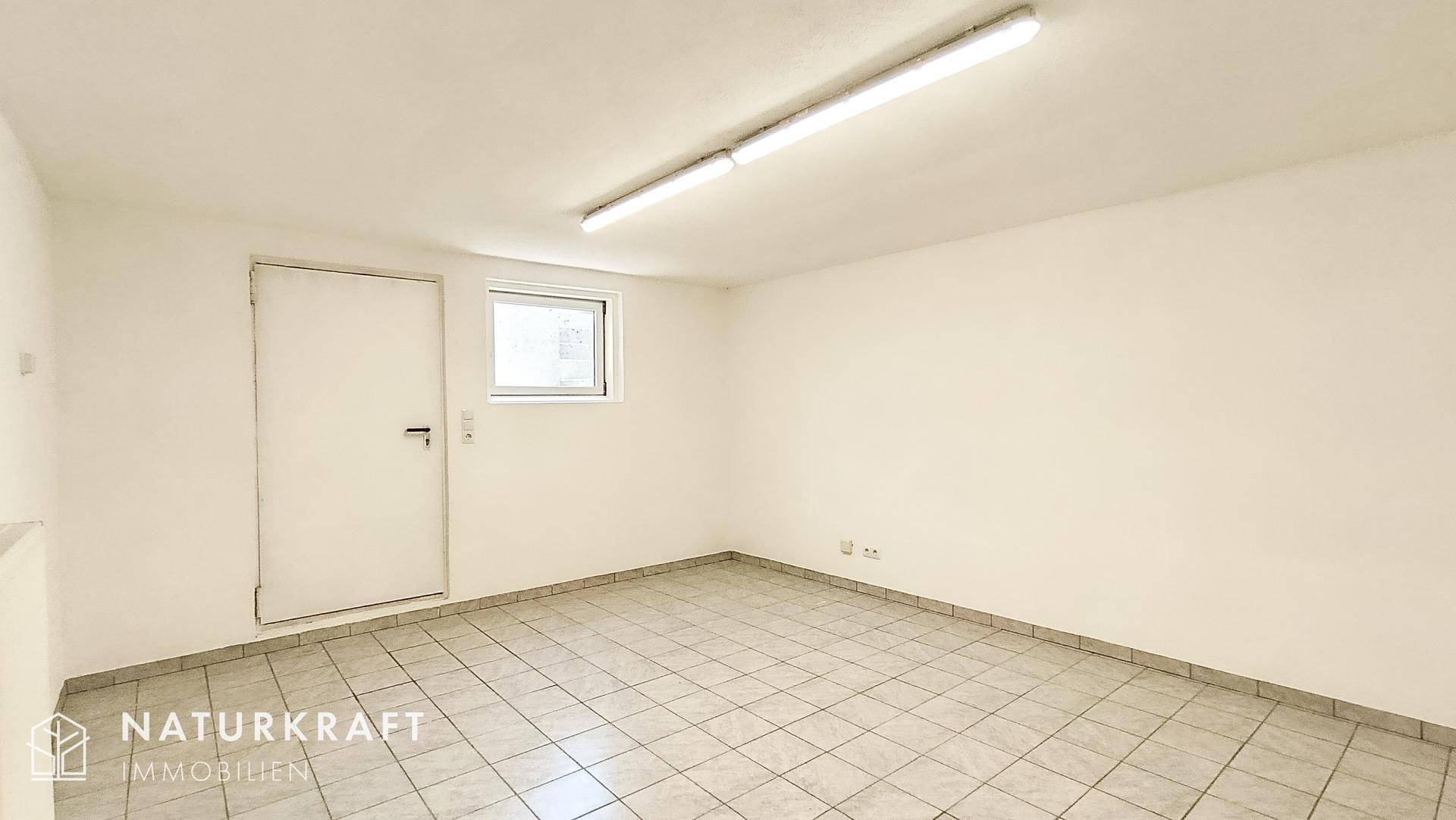 Heller, leerer Kellerraum mit Fliesenboden und weiß gestrichenen Wänden.